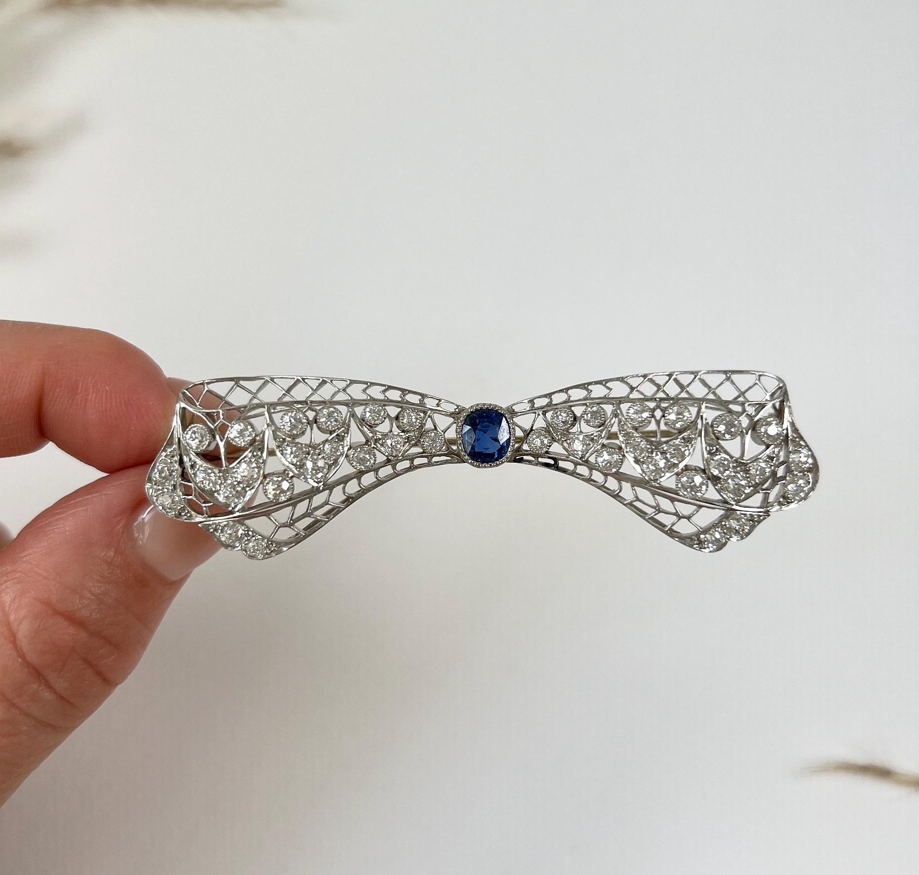 Antique Bow Brooch

Platinum 

Circa 1920s

This exquisite art deco brooch is designed in the shape of a bow and adorned with diamonds and a single sapphire. The sapphire is an old cushion cut weighing 1.00 carat, with a deep blue colour. The bow's