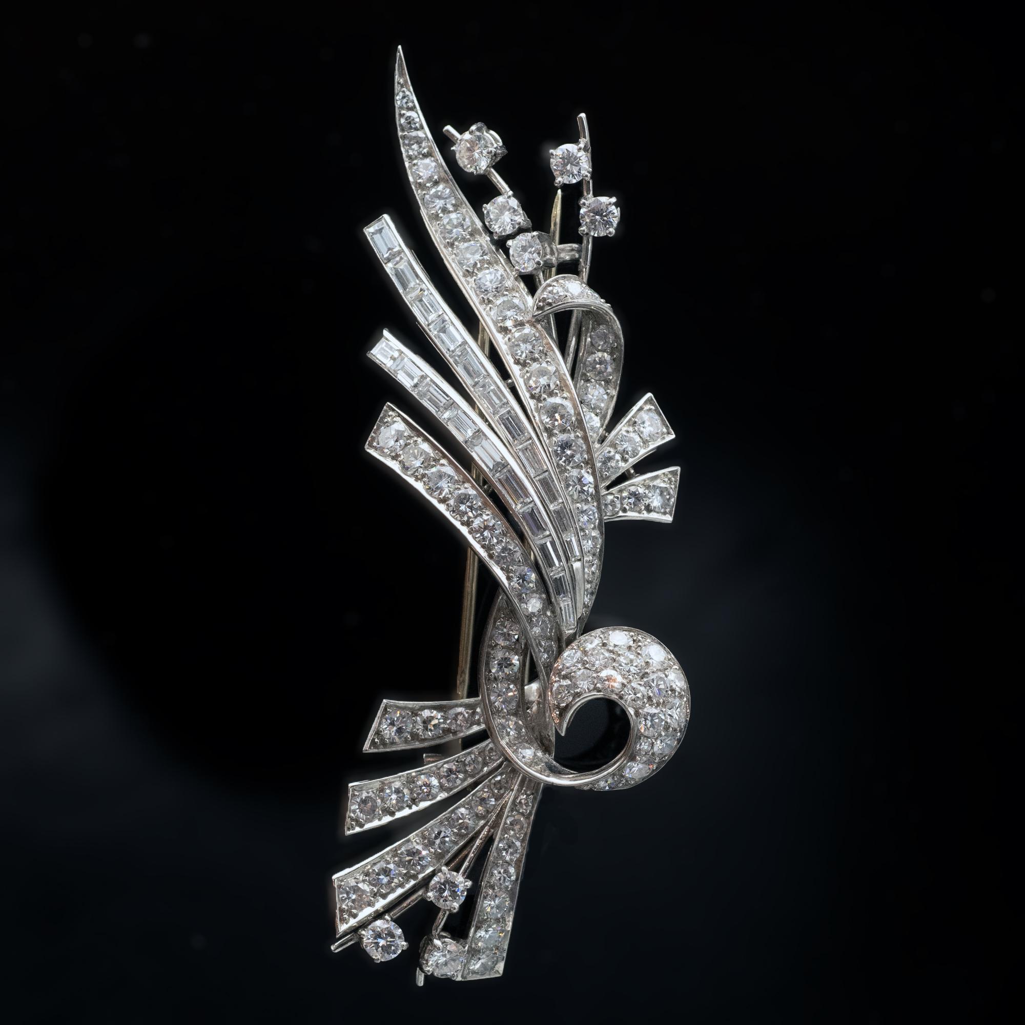 This platinum and diamond brooch has truly elegance and movement in its design. The diamonds, baguette and round are FG VS and weigh approximately 6.5 carat. Yhe make and condition are excellent. The brooch is in platinum but the actual pins are
