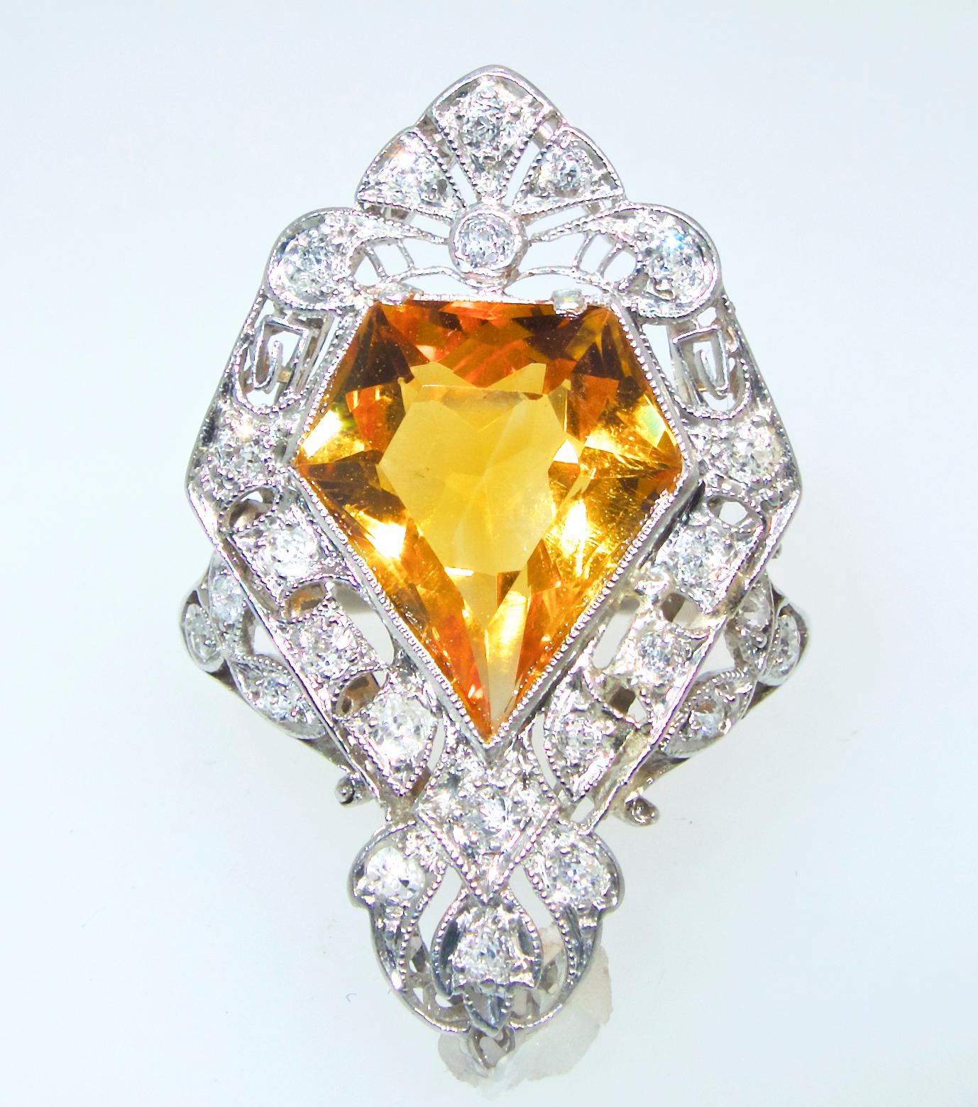 Edwardian platinum ring centering a fancy cut natural bright citrine weighing approximately 5 cts.   This shield-shaped center stone is accented with 24 old cut diamonds weighing approximately .58 cts.  This ring us 1 3/8 inches long and 13/16th