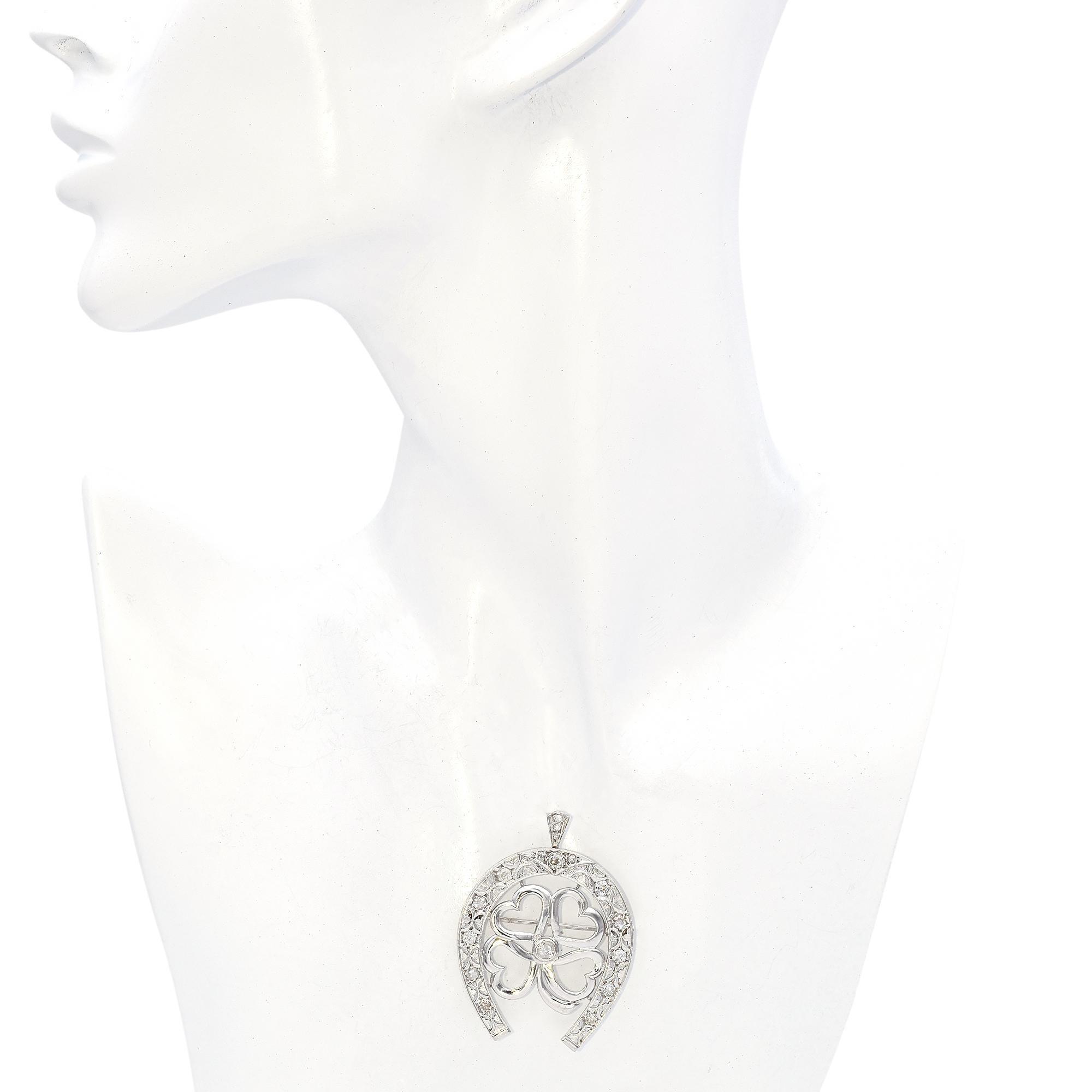 Das zarte Hufeisenmuster dieses Schmuckstücks ist mit funkelnden Diamanten verziert. In der Mitte befindet sich ein elegantes Kleeblattmotiv mit herzförmigen Blütenblättern, die anmutig in einem zentralen Diamanten zusammenlaufen. Die durchbrochene