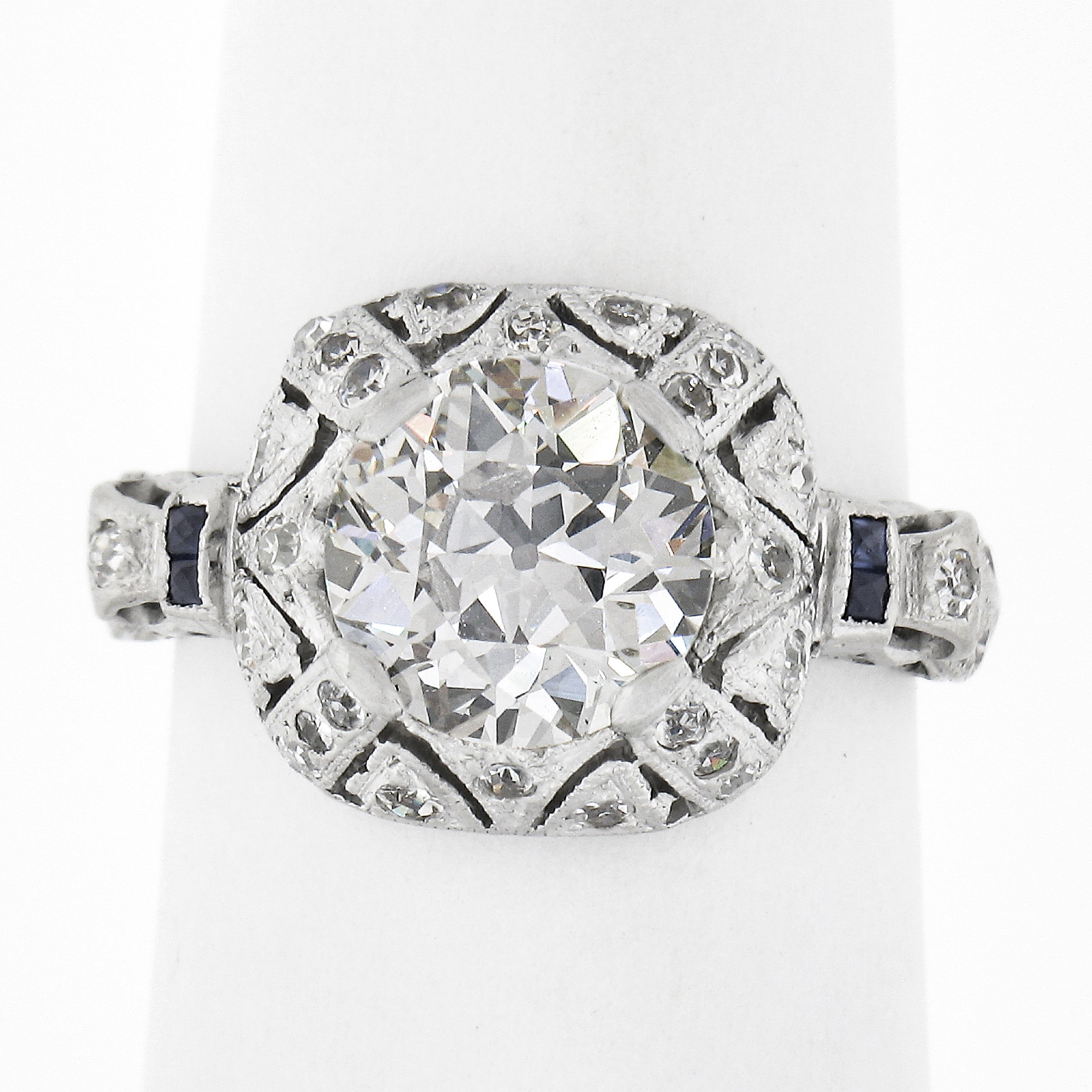 This fancy and uniquely designed antique engagement ring is from the early art deco period and crafted in solid platinum. It features a gorgeous, large GIA certified old European cut diamond neatly set at the center of the puffed cushion shaped