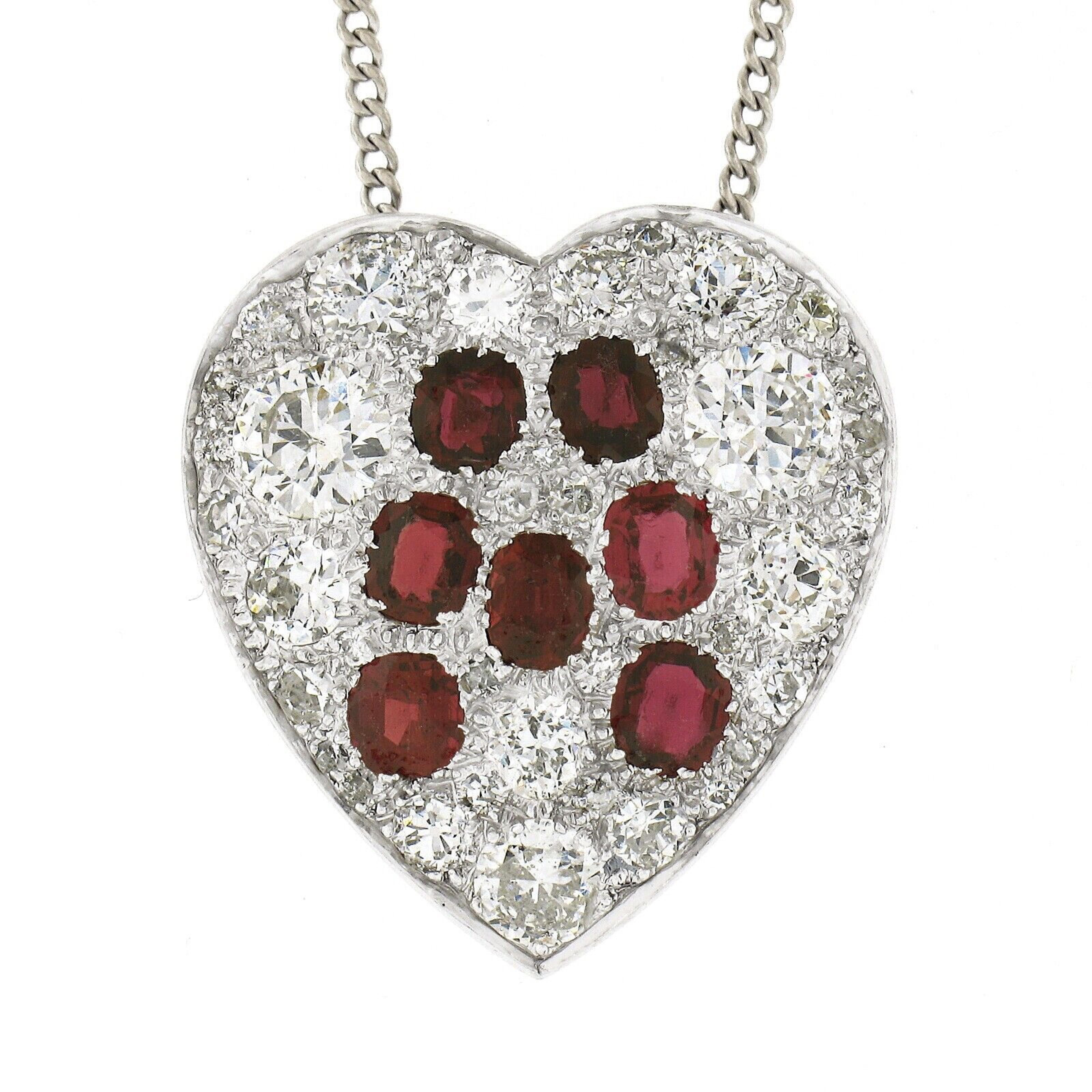This breathtaking antique pendant was crafted in solid platinum during the 1930-40's and features a large and slightly domed heart shaped pendant that is completely drenched in fine quality rubies and diamonds throughout. The 7 old oval cut rubies