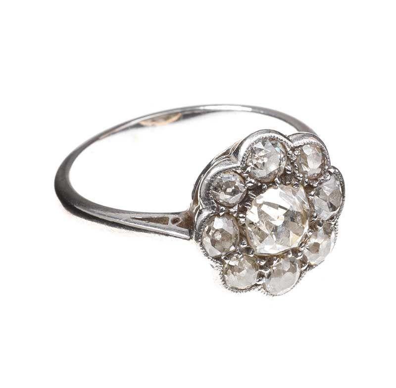 Diamond weight: Approx. 1.20 carat
Ring size: UK size O / US size 7
Weight: 3.5g.

Antique platinum and diamond daisy cluster ring; featuring a central old-mine cut diamond enhanced by smaller old-mine cut diamonds in a charming antique daisy