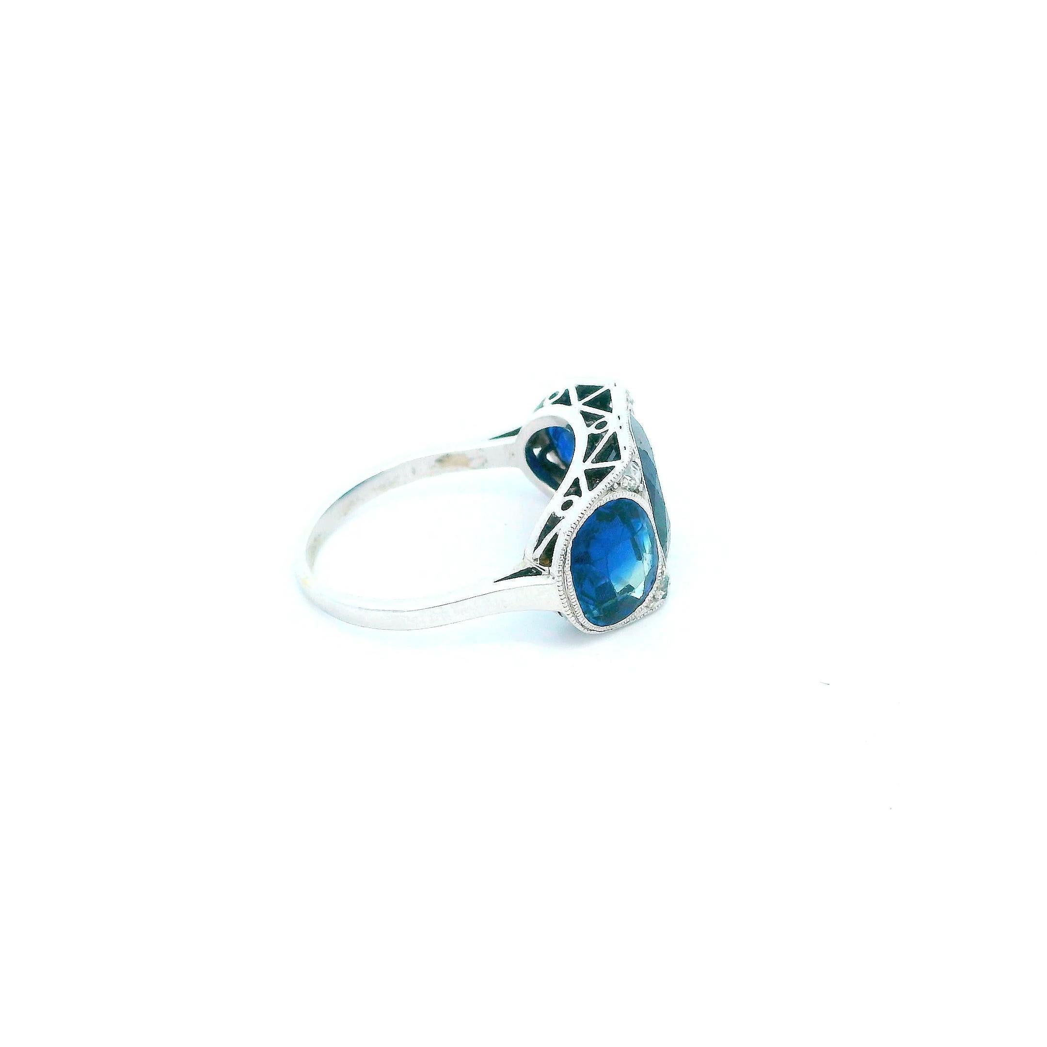 Antiue & Elegant Platinum Blue Sapphire Ring. This striking ring is crafted in platinum, featuring a captivating antique cushion cut blue sapphire at the center. Flanking the center stone are two additional antique cushion cut blue sapphires,