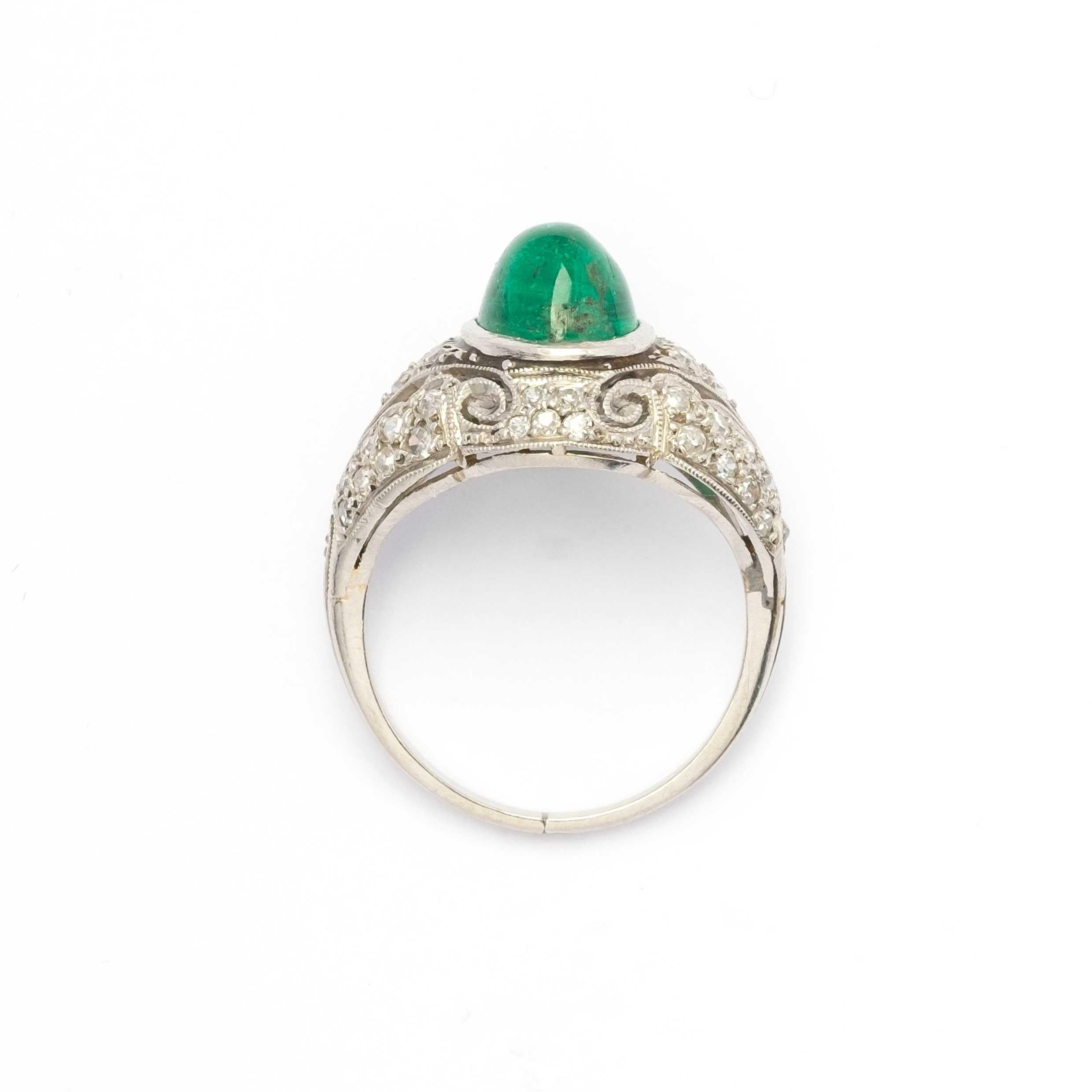 Une superbe bague originale du début des années 1900, réalisée en platine avec un design raffiné en forme de dôme, typique du style Liberty / Art Déco. En son centre brille une émeraude naturelle taillée en cabochon d'environ 1,5 carat, d'une