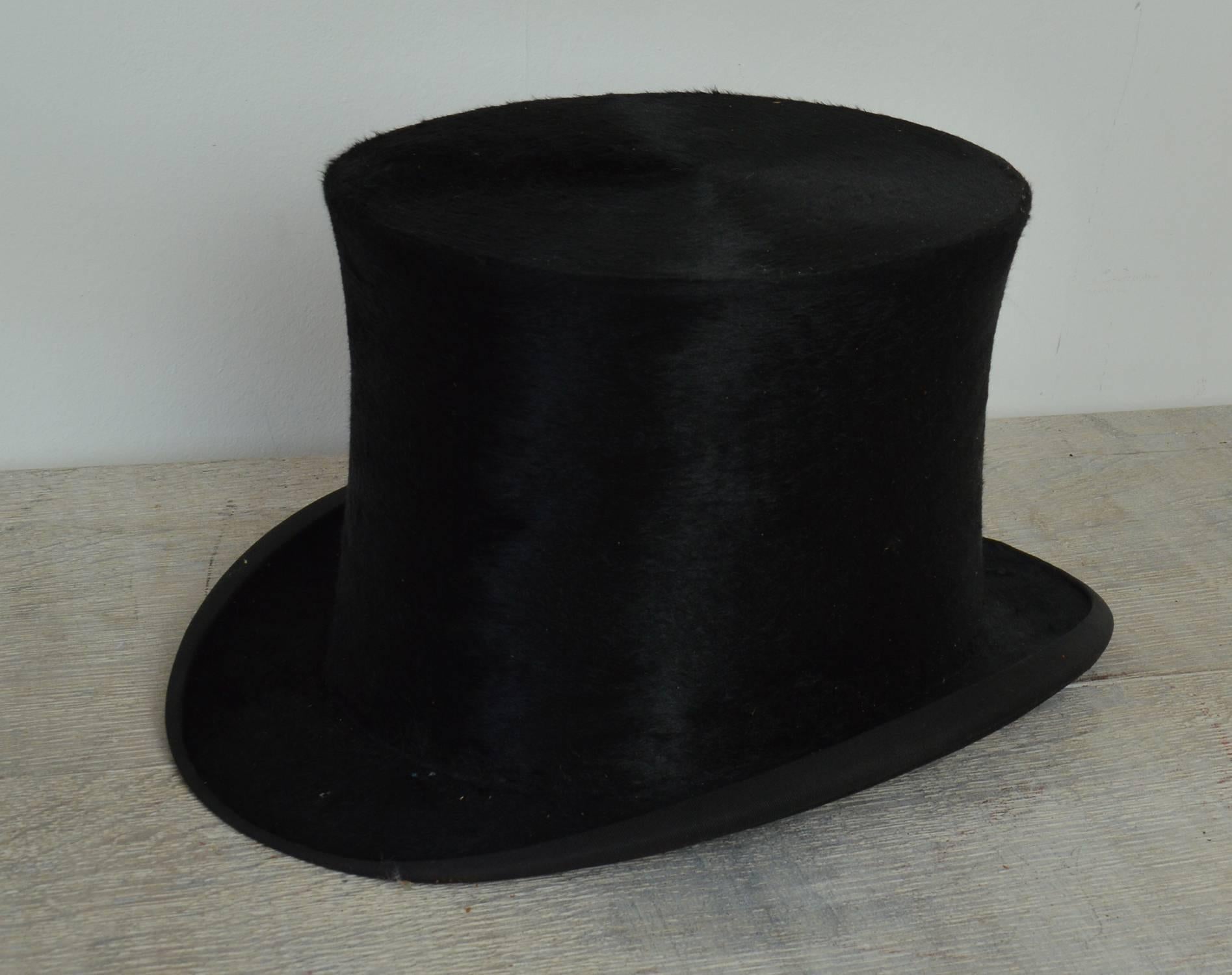 A very fine plush silk top hat in excellent wearable condition.

The interior is made of cream satin and fine cream leather with a printed armorial makers mark at the top.

Their is no evidence of the size on the hat but I have calculated it to