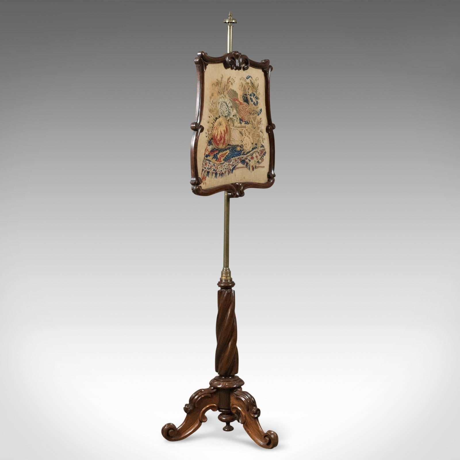 This is an antique pole screen, early Victorian fire screen, circa 1840.

Raised on a robust rosewood Stand with good colour and grain interest
A tripod of beautifully carved cabriole legs featuring C' scrolls, carved knees and scrolled toes
An