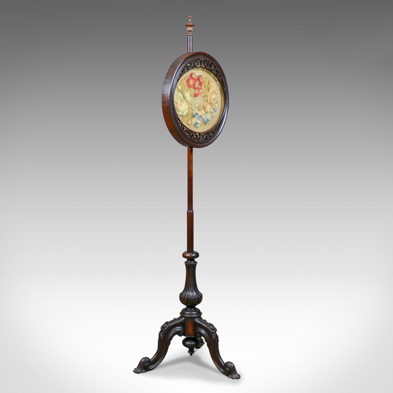 This is an antique pole screen, an English, Regency fire screen in rosewood with crewelwork, needlepoint panel dating to the early 19th century, circa 1820.

Raised on a robust rosewood stand with good color and grain interest
A tripod of