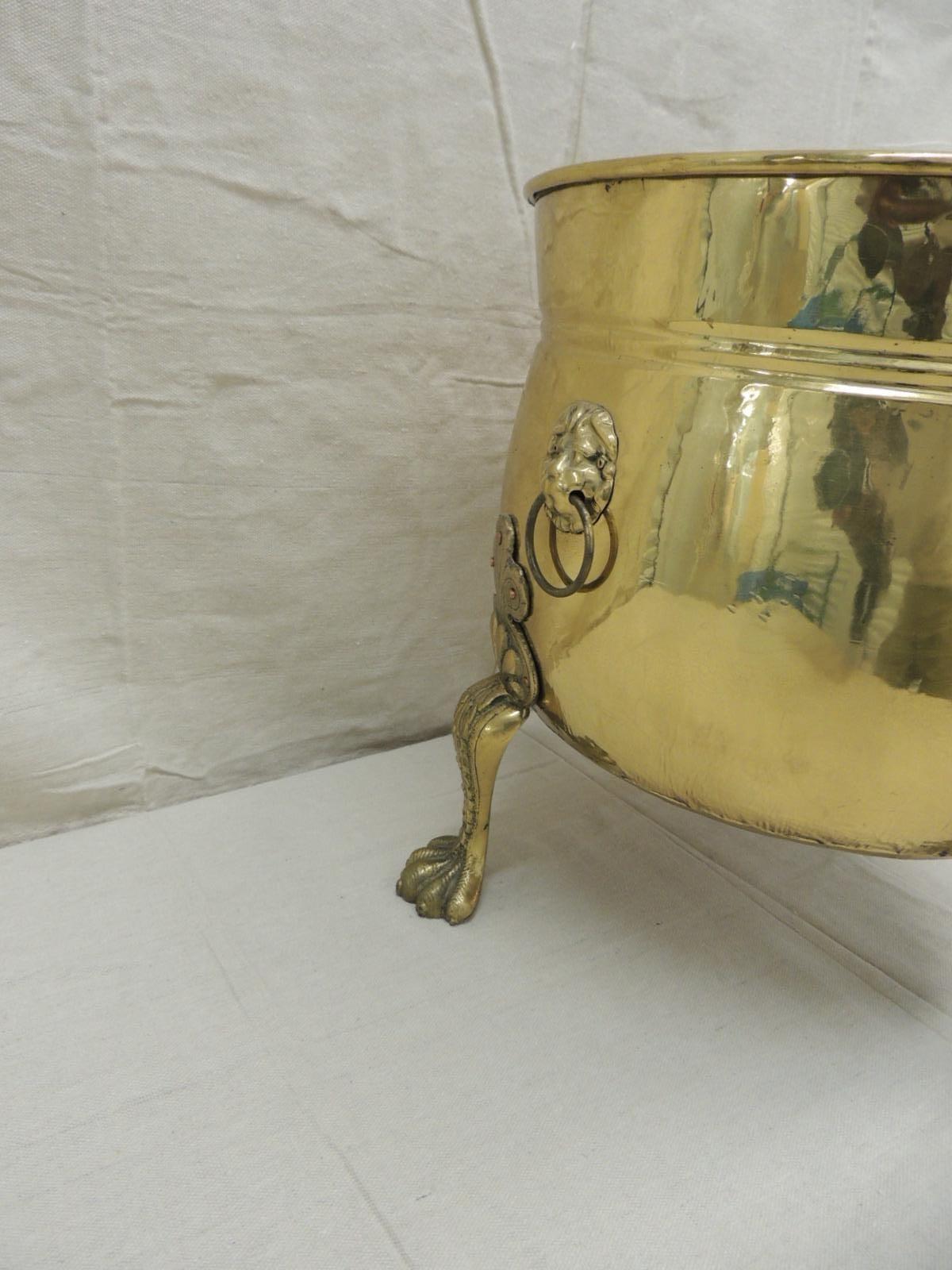 Antique polished brass plant/fireplace log holder CAULDRON
Round vessel with lion heads with handles attached and lions pouf feet (three)
Made in the United Kingdom and stamped craftsmen hand-hammered in England. The flower pattern around the base