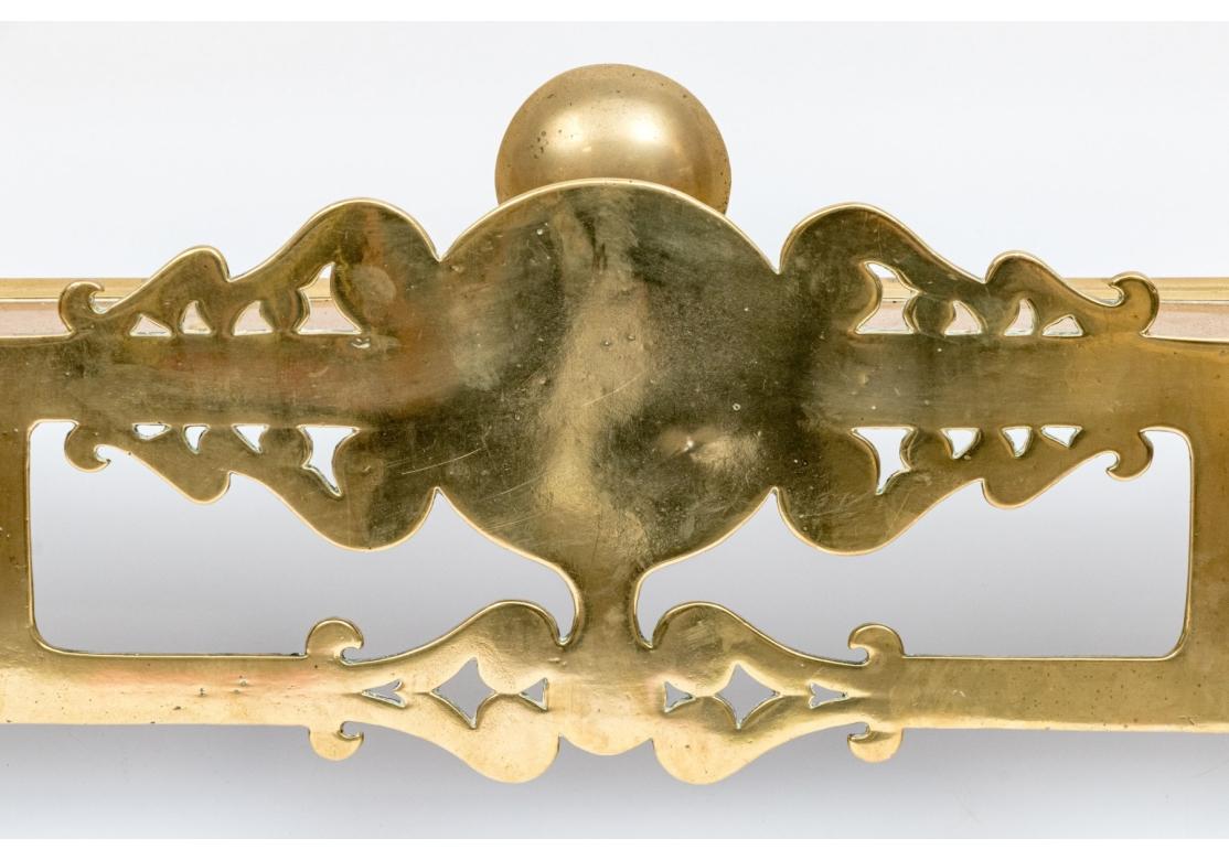 A fine Antique Brass Fire Fender with a particularly intricate form and decorative presentation. Heavy and solid polished brass deep fire fender with shaped with two ends with long side with openwork decorative motif. With good weight and solidity.