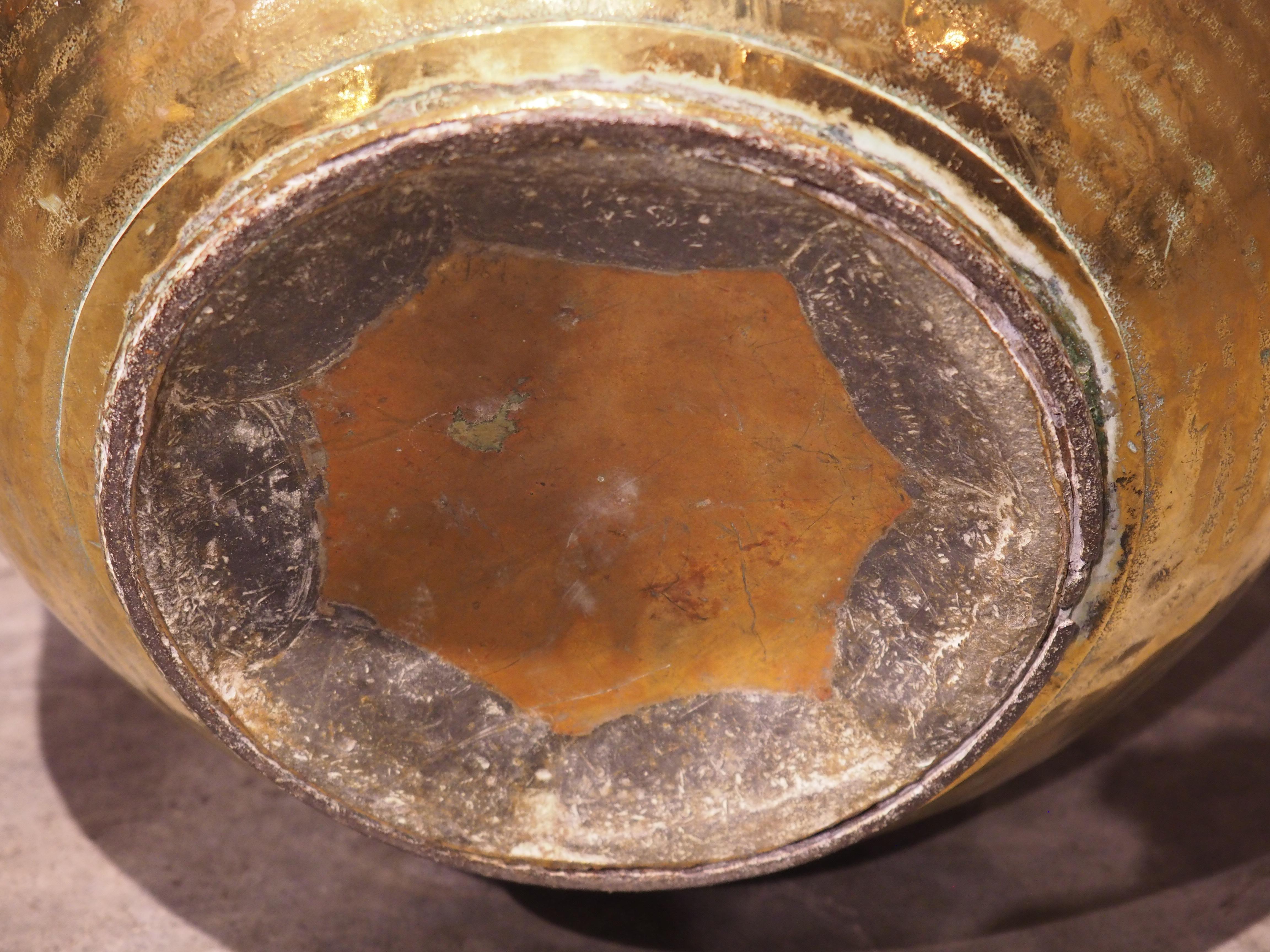 Rom Normandy, France, this polished brass milk jug was hand-crafted circa 1850. The outside of the stocky container was lightly textured by a technique called hammering. There is a scalloped collar where the neck attaches to the body. The mouth has