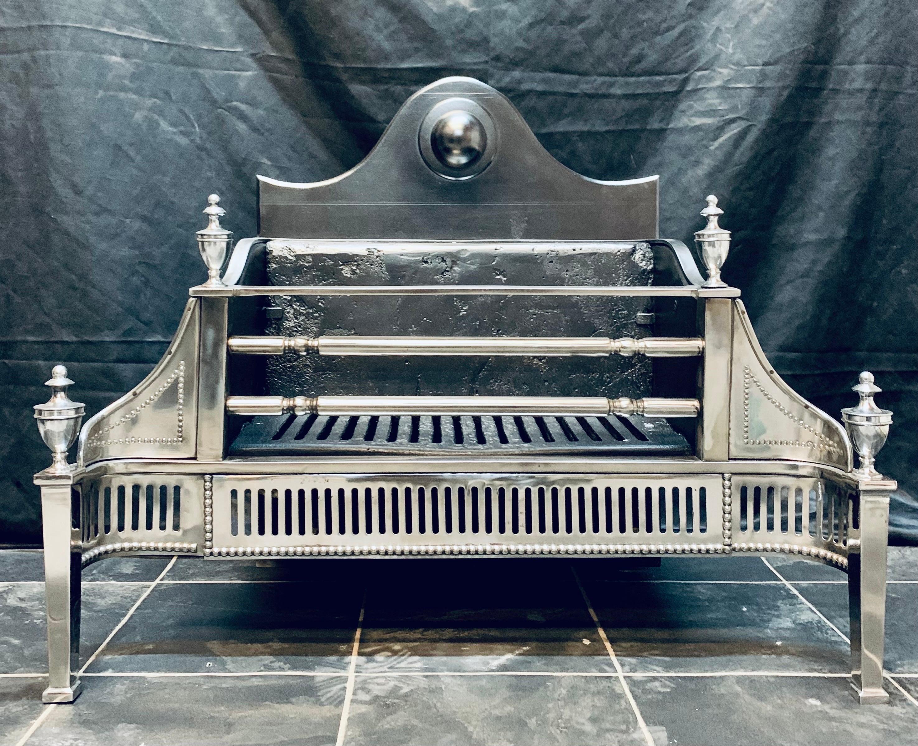 Antique Polished steel fire grate in the Georgian manner. A shaped cartouche back plate with a high relief half sphere, this in turn connects too a pair of high shaped fire cheeks, the three barred fire front flanked by square bar standards capped