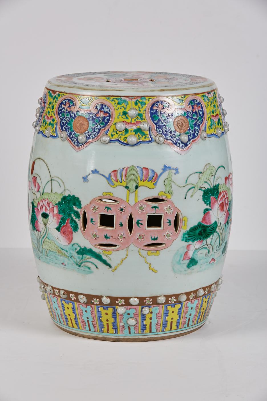 A polychrome Chinese porcelain garden seat having a banded border of insects and other symbols above a large flora water lily motif. Circular pierced coin design elements are symbolic of prosperity. Among the insects are butterflies which symbolize