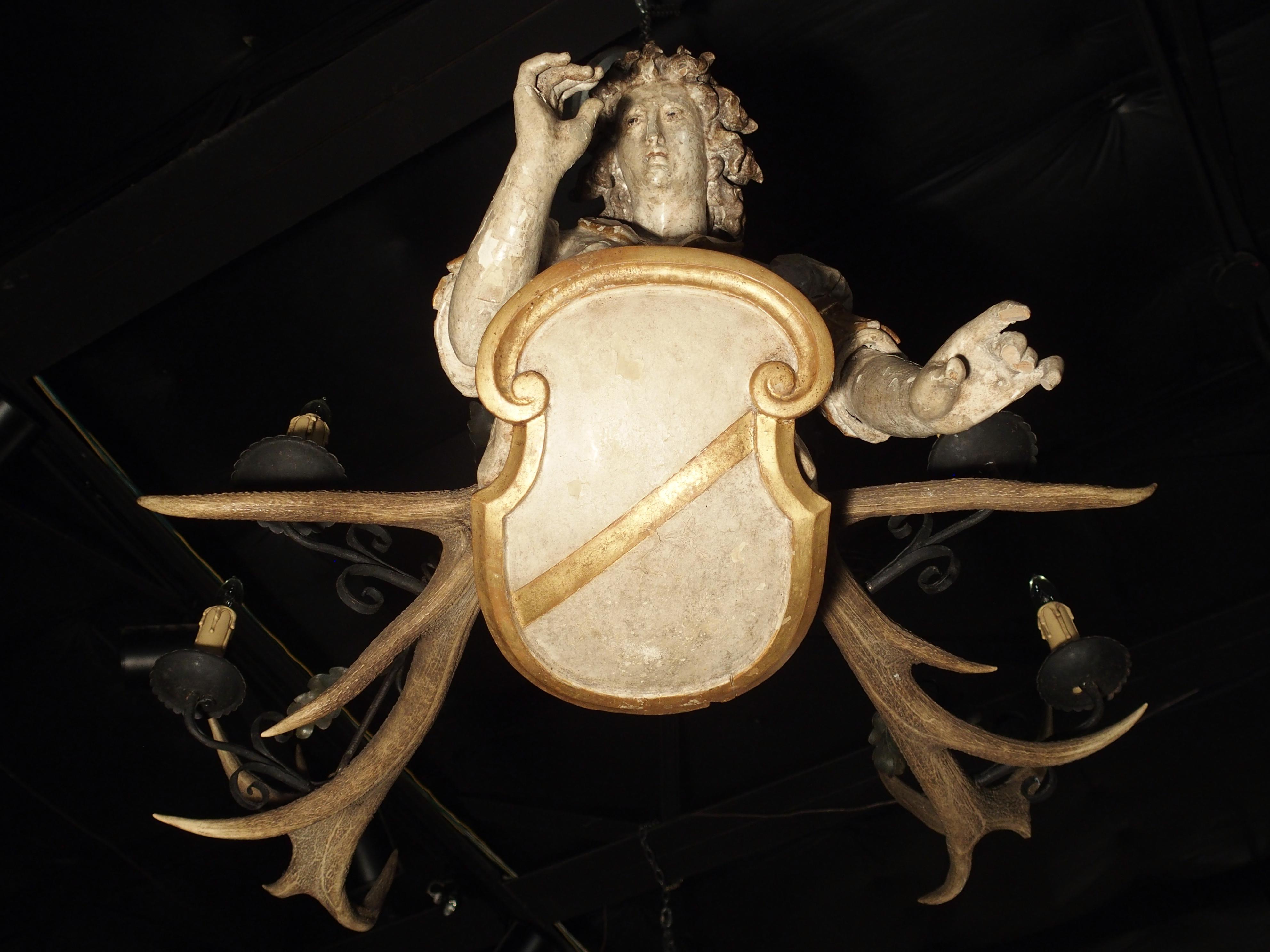 This fantastic figural chandelier is known in Germany as a Lustermannchen. The oldest examples on record date to the early 1400s, and were only made in Southern Germany. The combination of a carved wooden statue and large antlers made the perfect