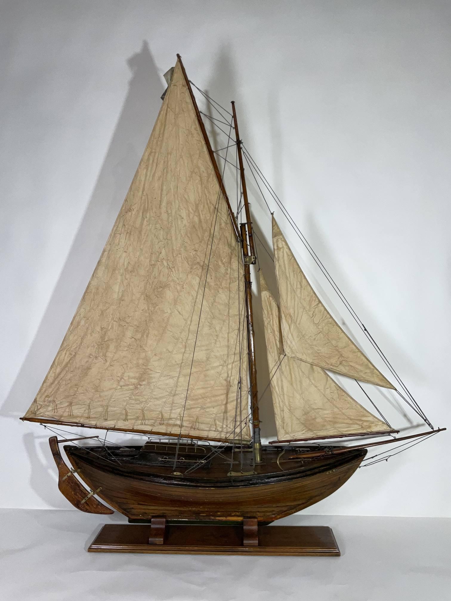 Un modello di sloop a doppia vela di un metro e mezzo dei primi del Novecento, armato con un completo di vele. Molti accessori in ottone. Lo scafo con struttura in tavole ha una bella finitura in vernice. Culla in Wood molto ben costruita. Da una