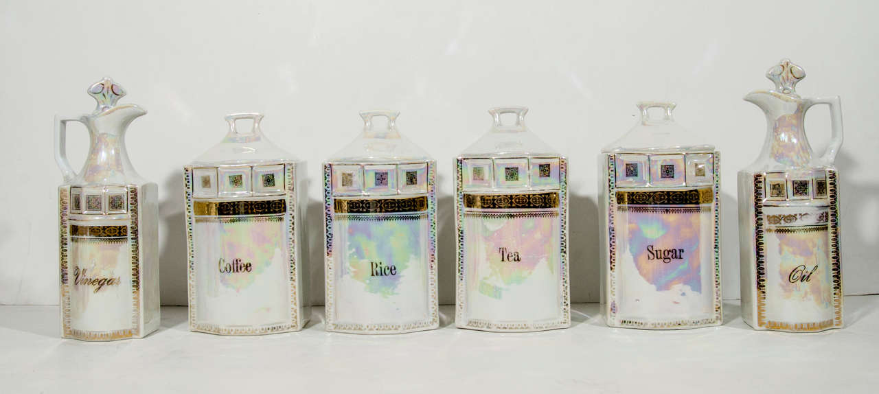 Handmade antique porcelain apothecary and spice canister set of twelve. Feature gilt details and iridescent metallic glaze or lusterware. The set includes four large canisters with lids (measuring 8.5 H x 4.5 D), six spice jars with lids (measuring