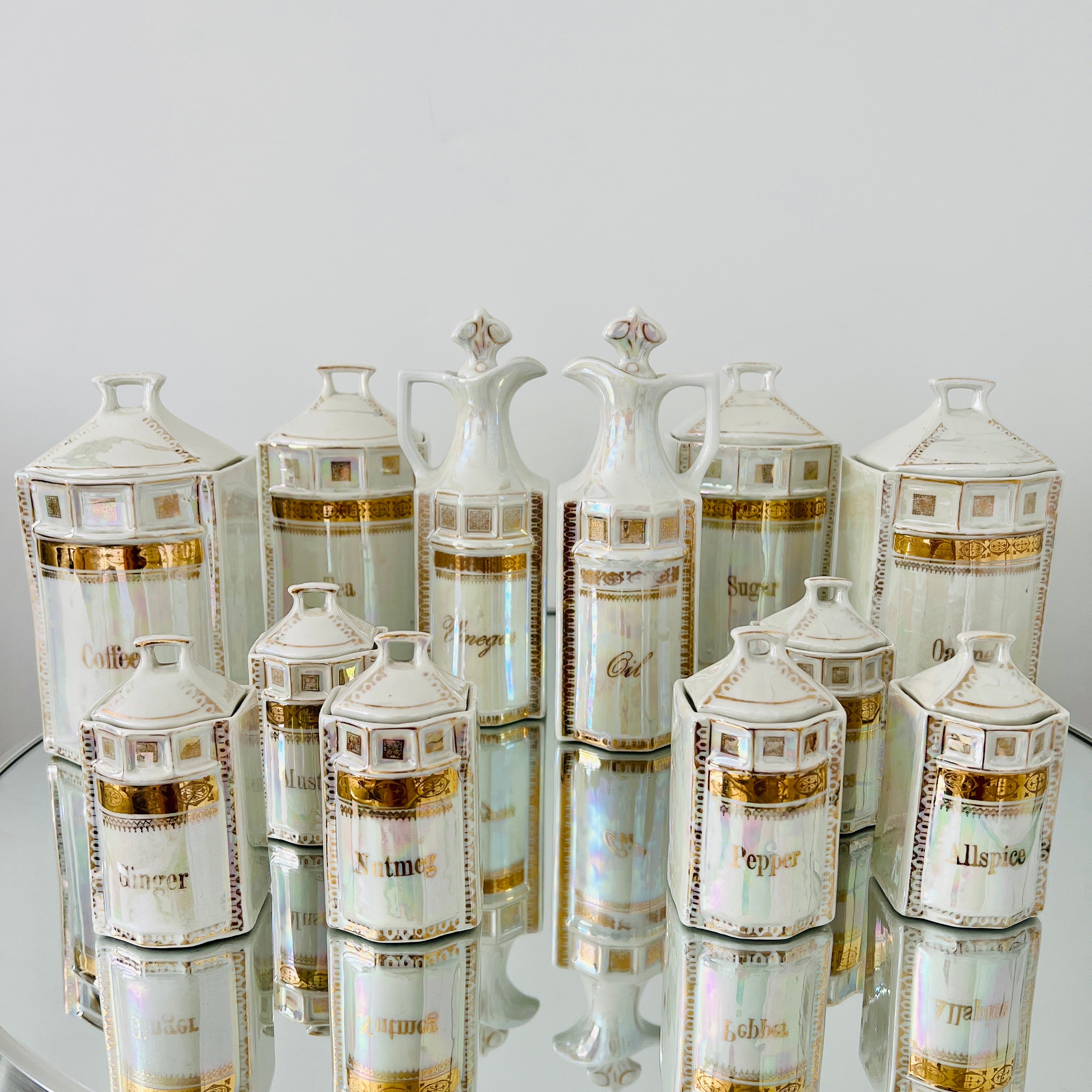 Handmade antique porcelain apothecary and spice canister set with 13 pieces. Hand-painted in 24K gold leaf with iridescent metallic glaze or lusterware. The set includes four large canisters with lids (measuring 8.5 H x 4.5 D), six spice jars with