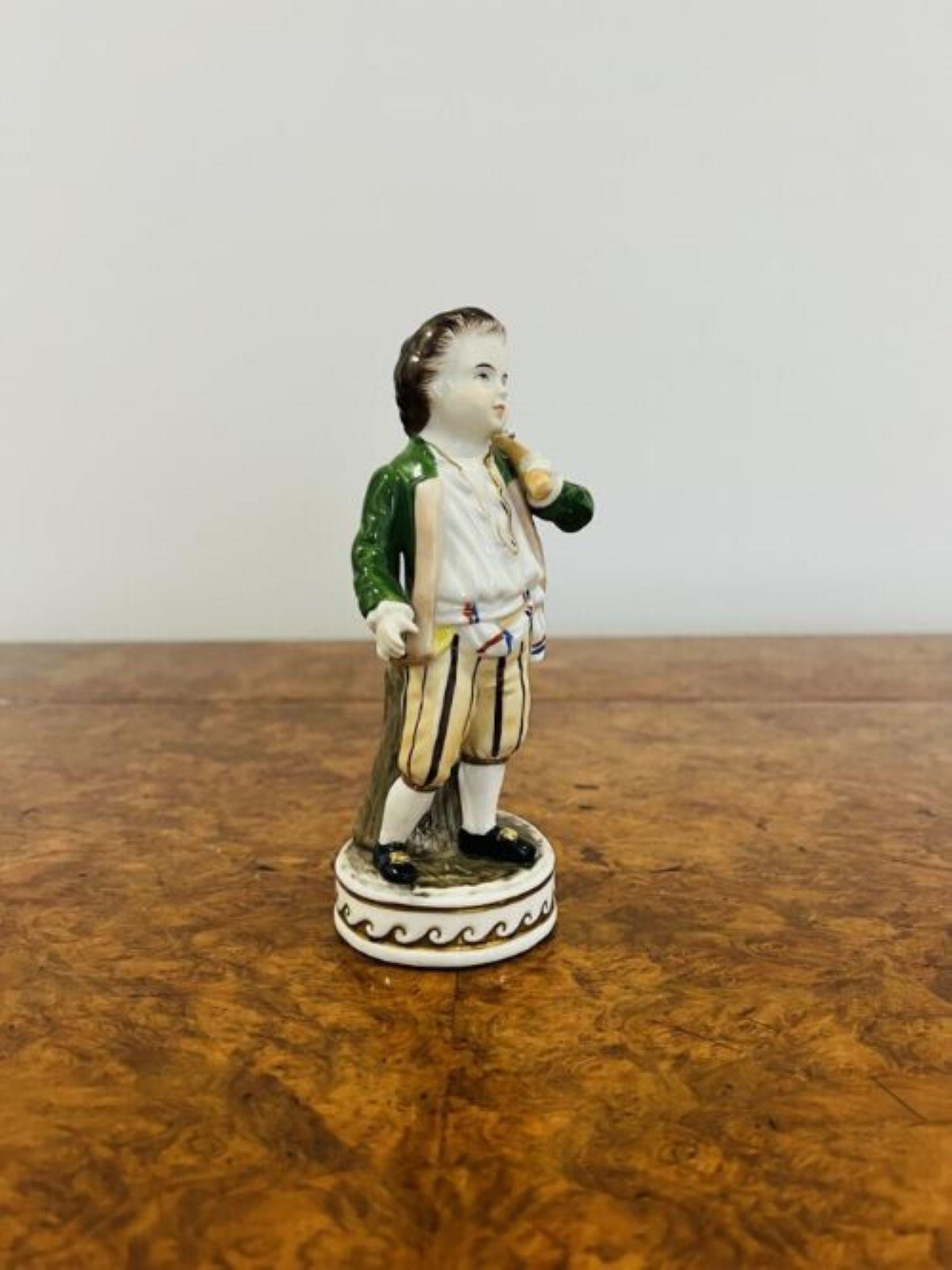 Antique porcelain continental figure having an antique porcelain continental figure of a child carrying a bag in wonderful coloured period clothing in stunning brown, green, cream and yellow colours standing on a circular gilded base. 