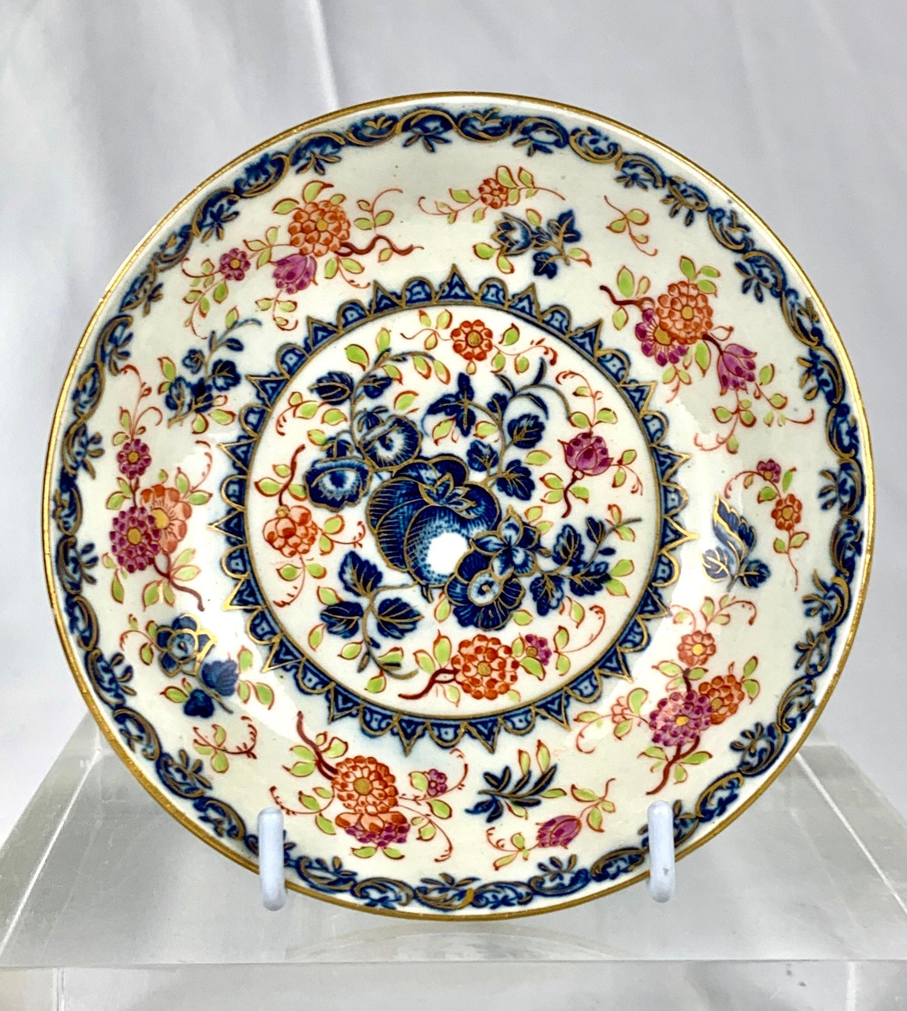 Diese Worcester-Tasse mit Untertasse aus der ersten Periode ist mit einem zarten Blumenmuster verziert.
Grüne Blätter und Blumen sind von Hand in Orange, Violett und Unterglasurblau gemalt, die mit Gold umrandet sind.
In der Mitte der Untertasse und