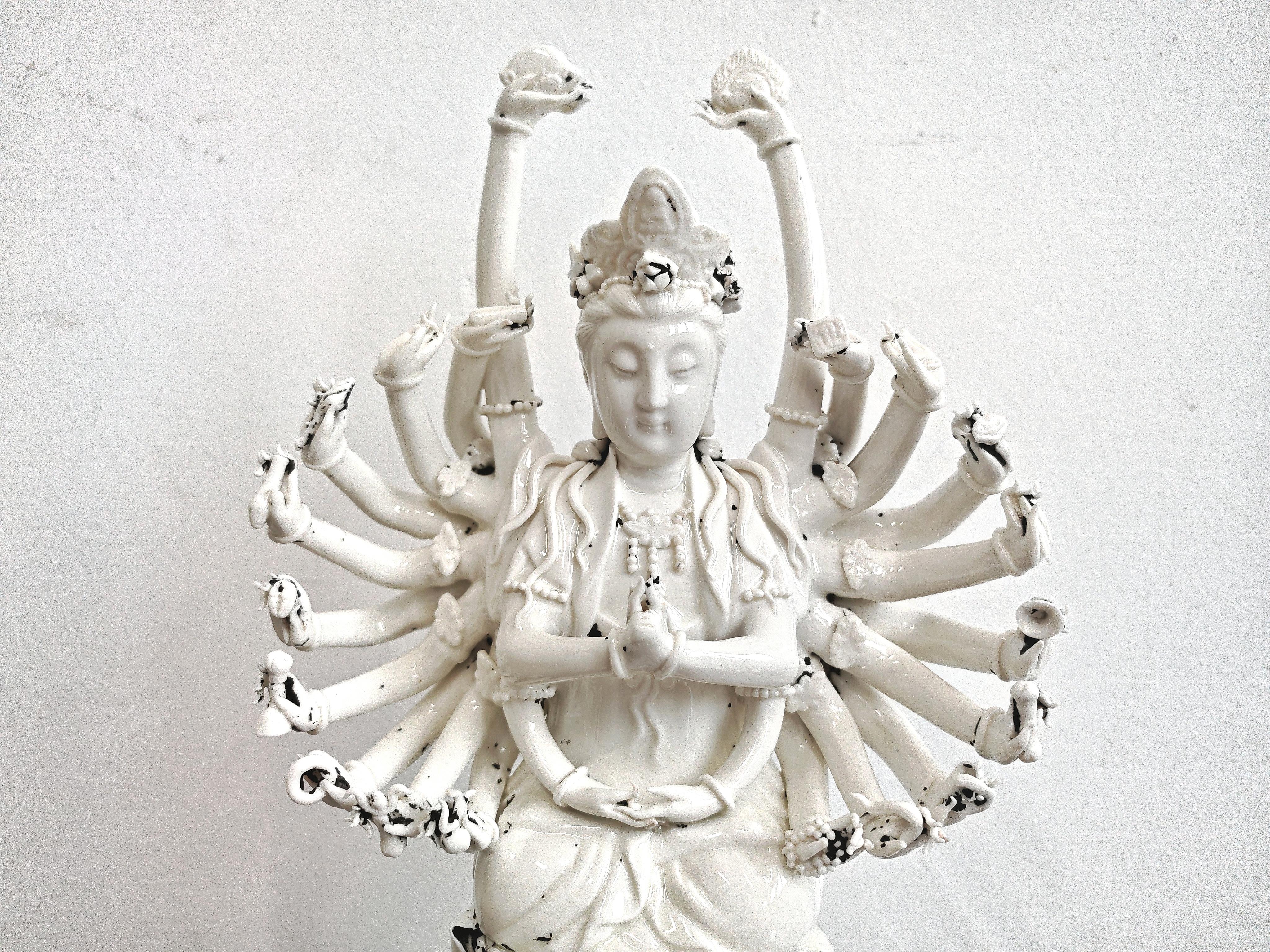 In diesem Angebot finden Sie eine wunderschöne und raffinierte Porzellanfigur von Guanyin, der esoterischen buddhistischen Gottheit mit mehreren Armen und einem sitzenden Buddha vor ihrer Krone, die in Meditation auf einer riesigen Lotusblume sitzt.