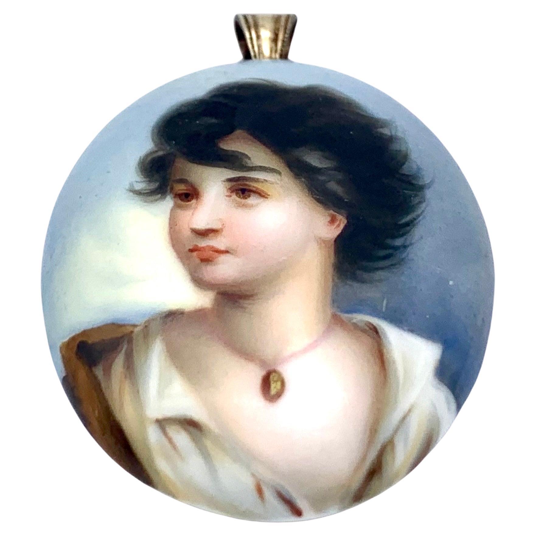 This charming locket was made in 1870 ca. It is made entirely out of bisque porcelain, The eyelet os made out of silver plated brass, the locket fitting is made out of glass. The locket features a coloured print of a young girl in a brown red jacket