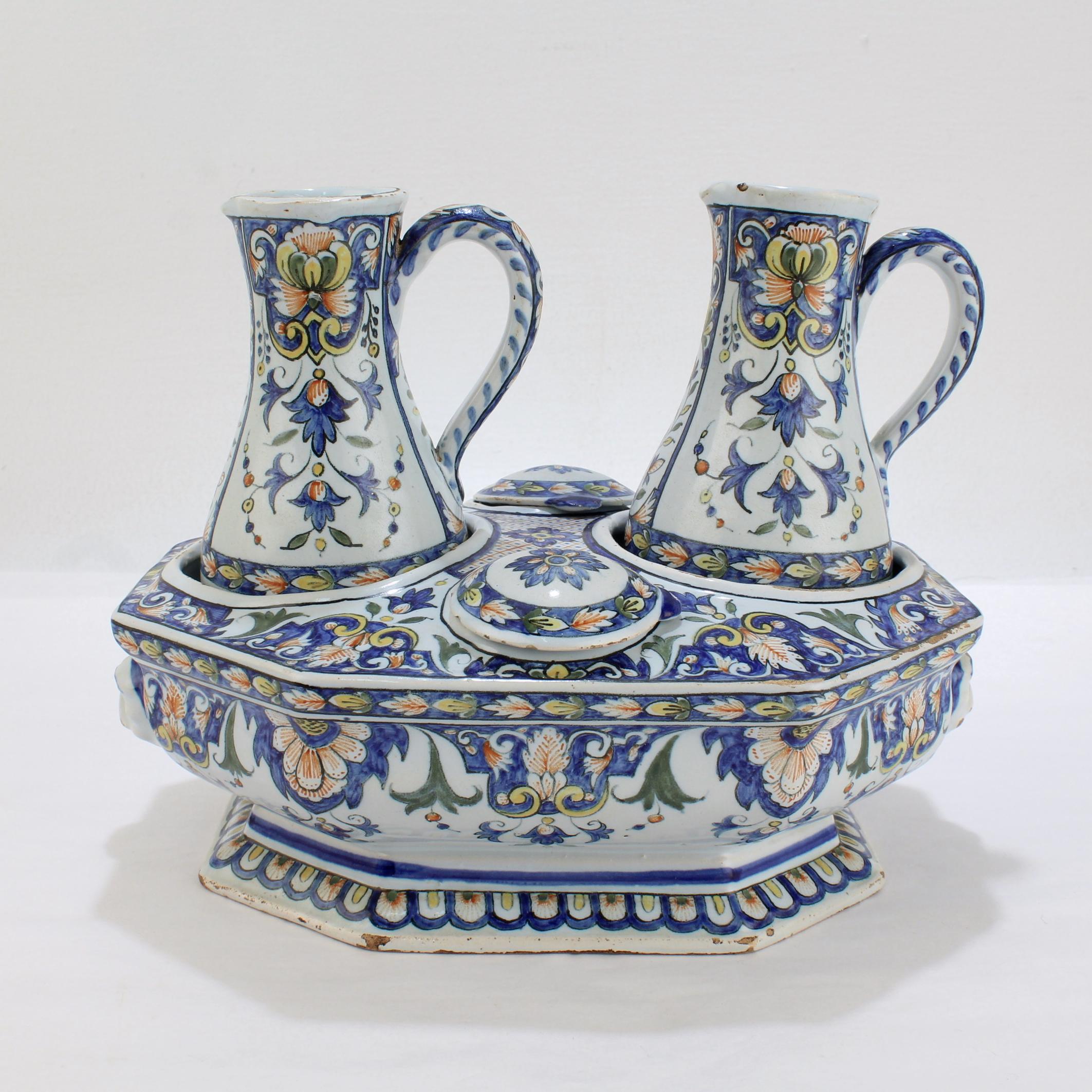 A very fine antique French Porquier Beau faience cruet stand.

Complete with the original base, ewers or small pitchers, and conforming lids.

Decorated in the Rouen style with blues, greens, yellows and oranges.

The base has stylized lion face