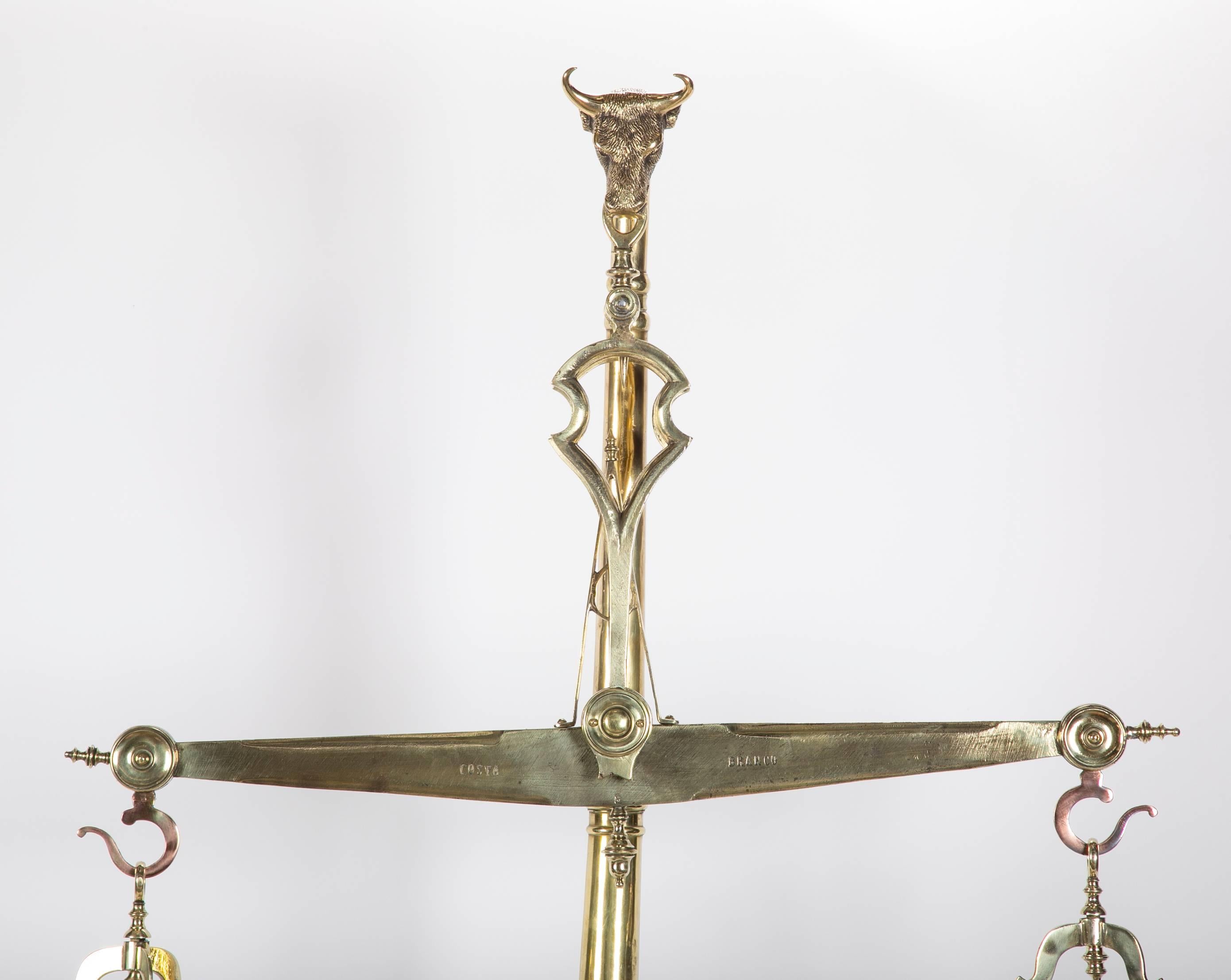 An antique brass Portuguese butcher's scale with bull's head figure.
    