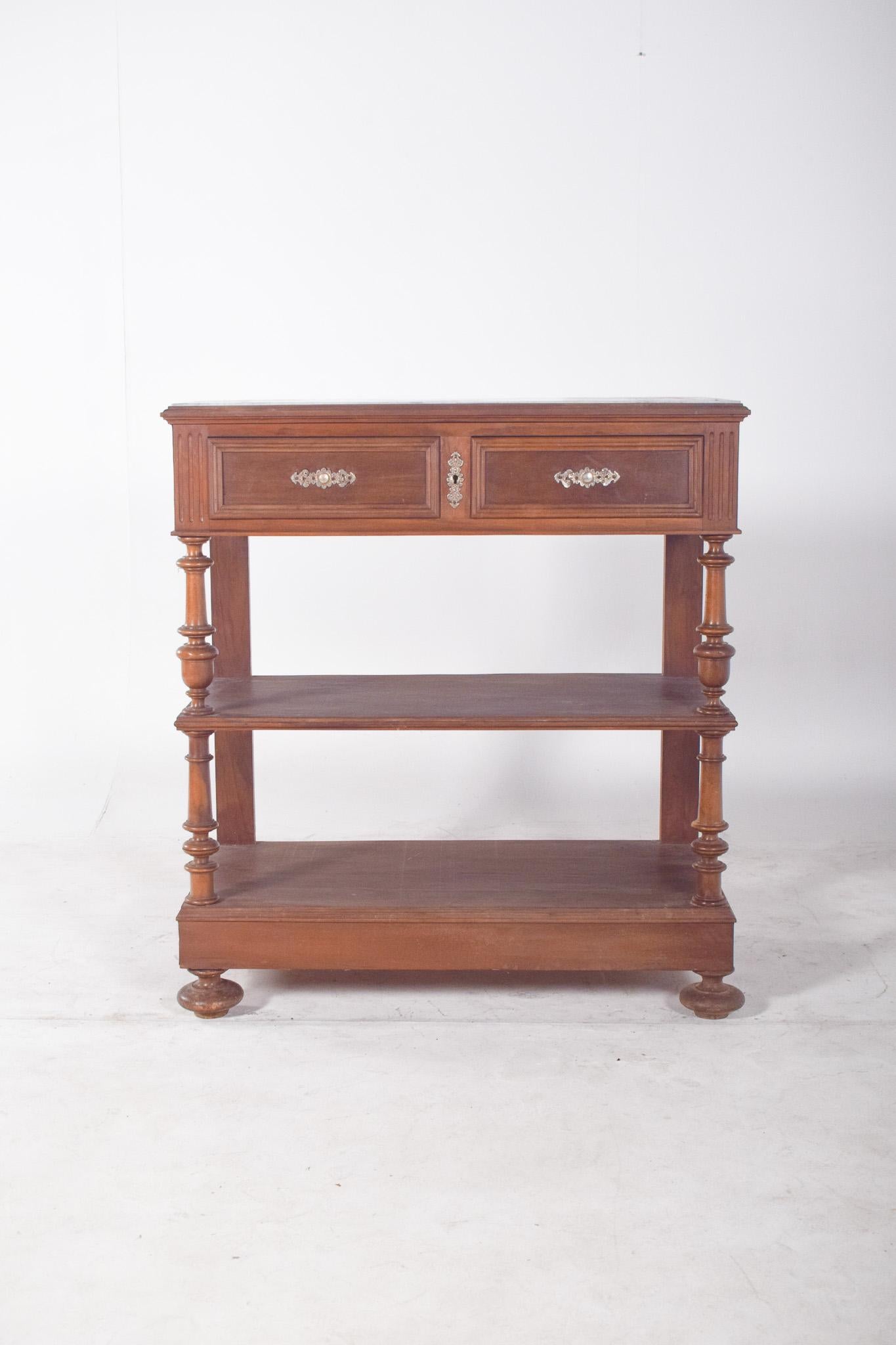 Cabinet de sculpture de style Henry II. Le corps supérieur est composé de deux tiroirs symétriques avec des frises encadrées et des poignées en métal décorées au centre, ce qui ajoute de la sophistication à l'ensemble.
Il est soutenu par des