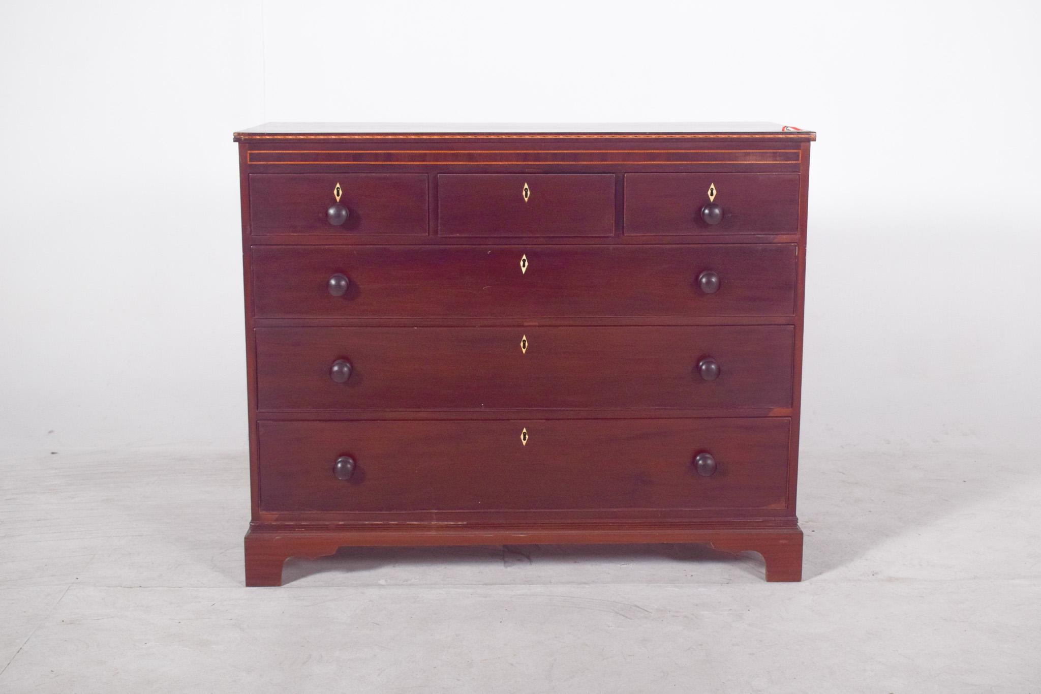 Commode en acajou, style D. A Style. Il présente un corps rectiligne avec quatre grands tiroirs disposés verticalement, surmontés de trois tiroirs plus petits placés côte à côte. Les poignées rondes en bois tourné, discrètes et fonctionnelles, sont
