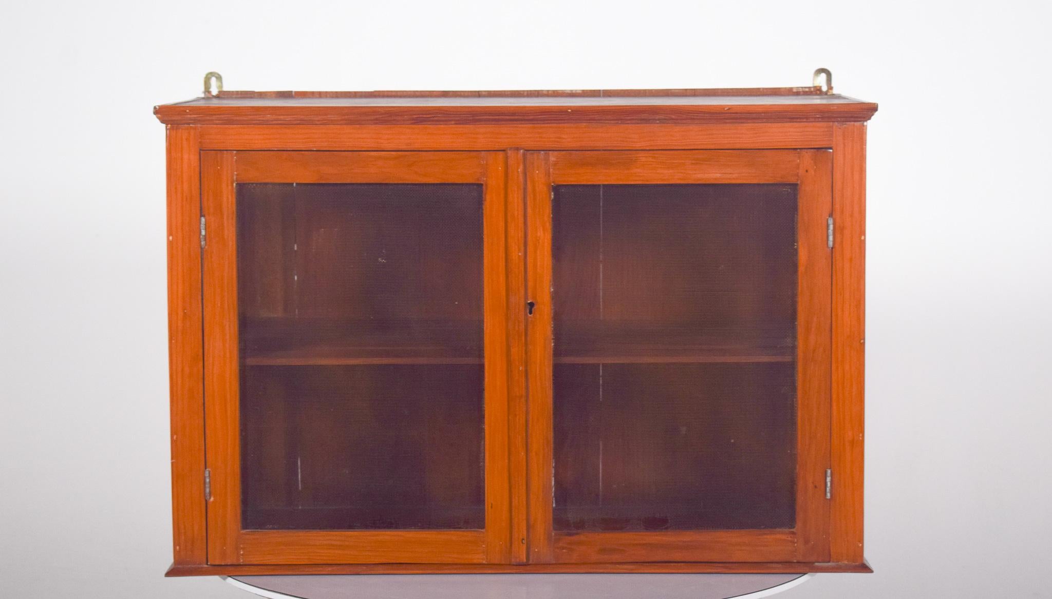 Rustic wall cabinet. In wood, with a simple finish, it has two front doors with fine mesh instead of glass, a typical feature of this era, allowing for internal ventilation, which makes it ideal for storing food or utensils.
The sides are also made