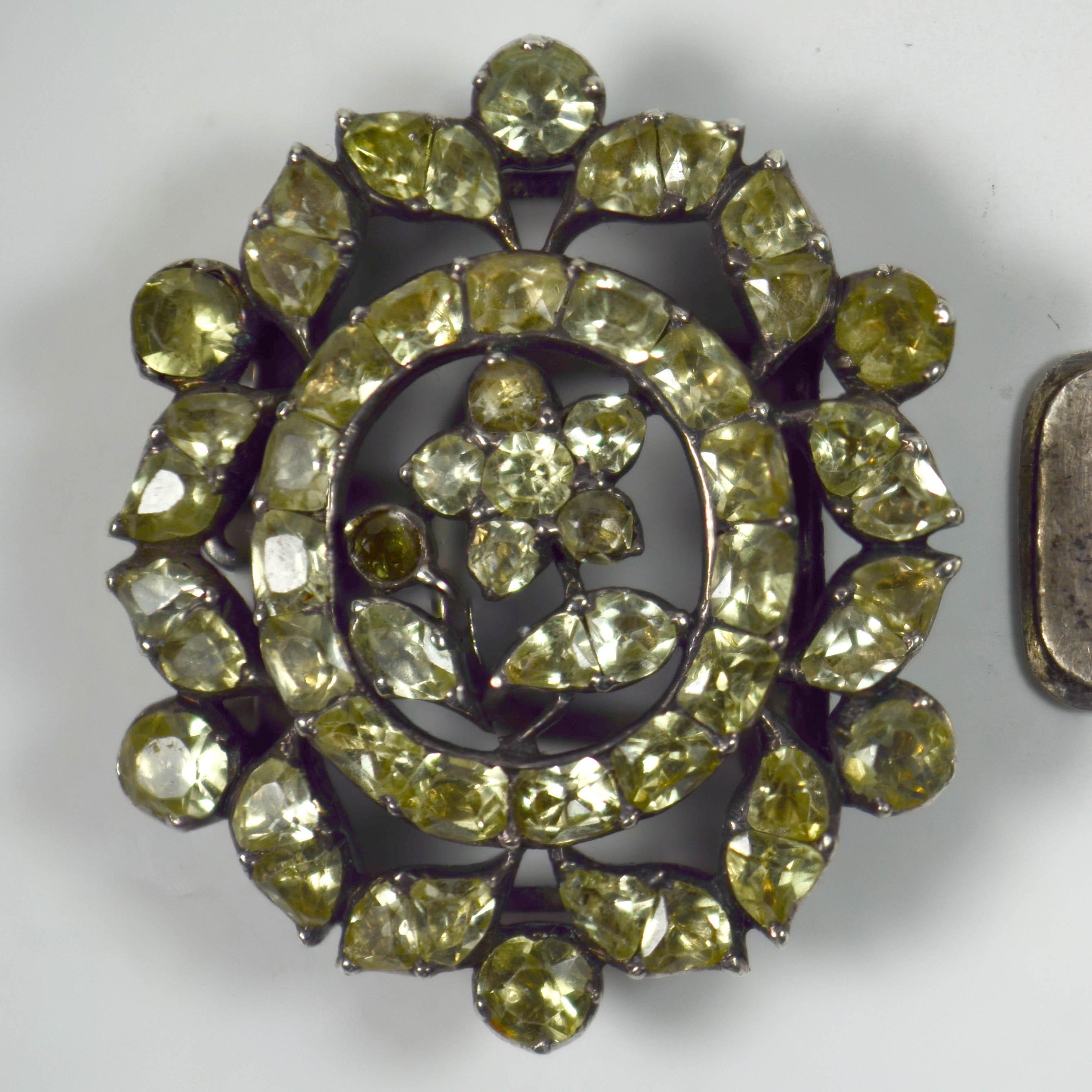 An antique clasp set with pale green chrysoberyl in a floral design mounted in silver. Portuguese c.1750. 

The 57 chrysoberyl foil-backed stones are original to the piece, and are in good condition showing very little wear. No discolouration to