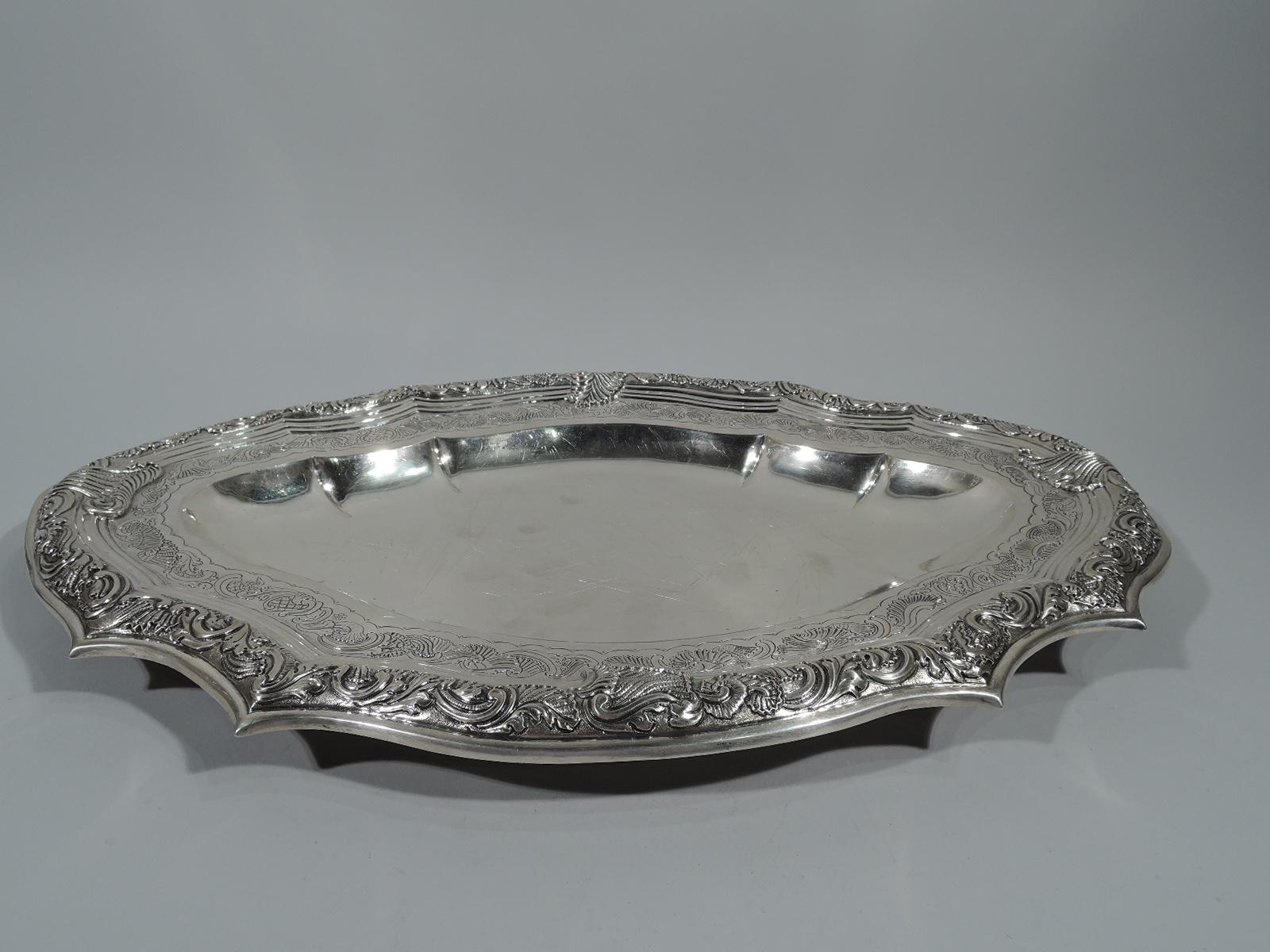 Antique Portuguese silver serving tray, late 18th century. Plain and shaped oval well. Shoulder has chased leafy-scroll-and-shell band between Vitruvian scroll and molded borders. Same embossed on rim with large overlapping shells. Fashionable
