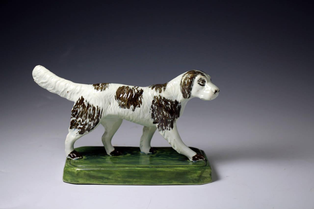A rare and naively modelled pottery figure of a setter dog standing on an oval base.
The figure is artistically modelled with good movement. 
The natural pigment oxide colouring is underglaze.