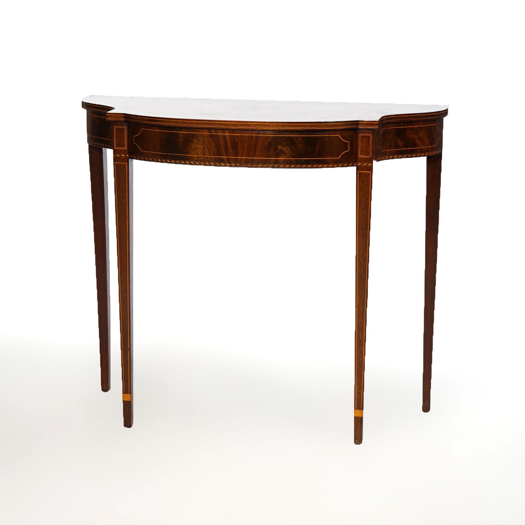 An antique side table by Potthast Brothers, Baltimore, Maryland offers flame mahogany construction in demi-lune form with satinwood inlay and banding throughout, raised on straight and tapered legs, maker label as  photographed, c1920

Measures-