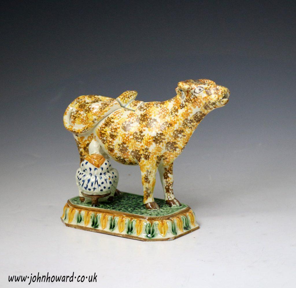 A exceptional fine and rare Prattware pearl ware pottery cow creamer with milk maid. Every feature on this figure exudes quality, the modelling of the milk-maid, the sublime touch of the tail tip on the cover, the finely executed and detailed base
