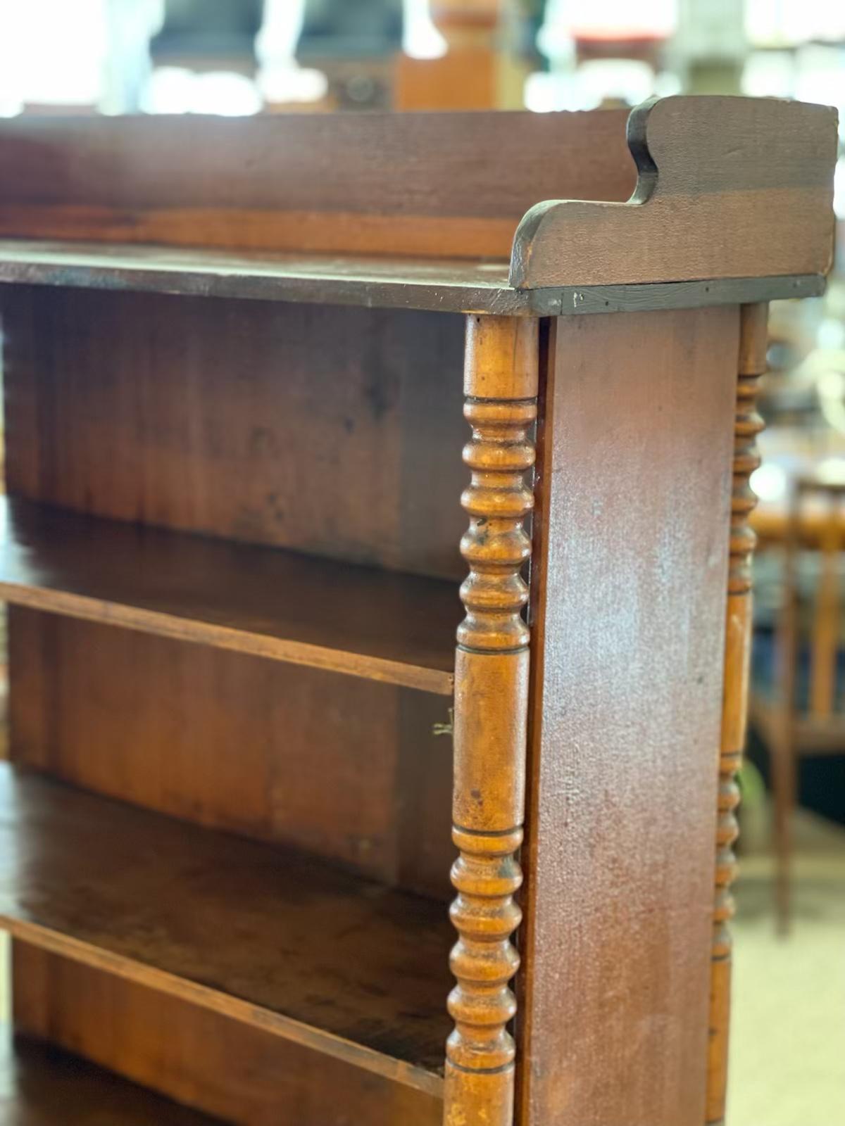  Antica libreria americana primitiva a giorno degli inizi del XIX secolo sollevata su colonne in legno massiccio tornite a mano. 
Questa libreria in legno massiccio ha una finitura originale e un'ottima patina. I ripiani non sono