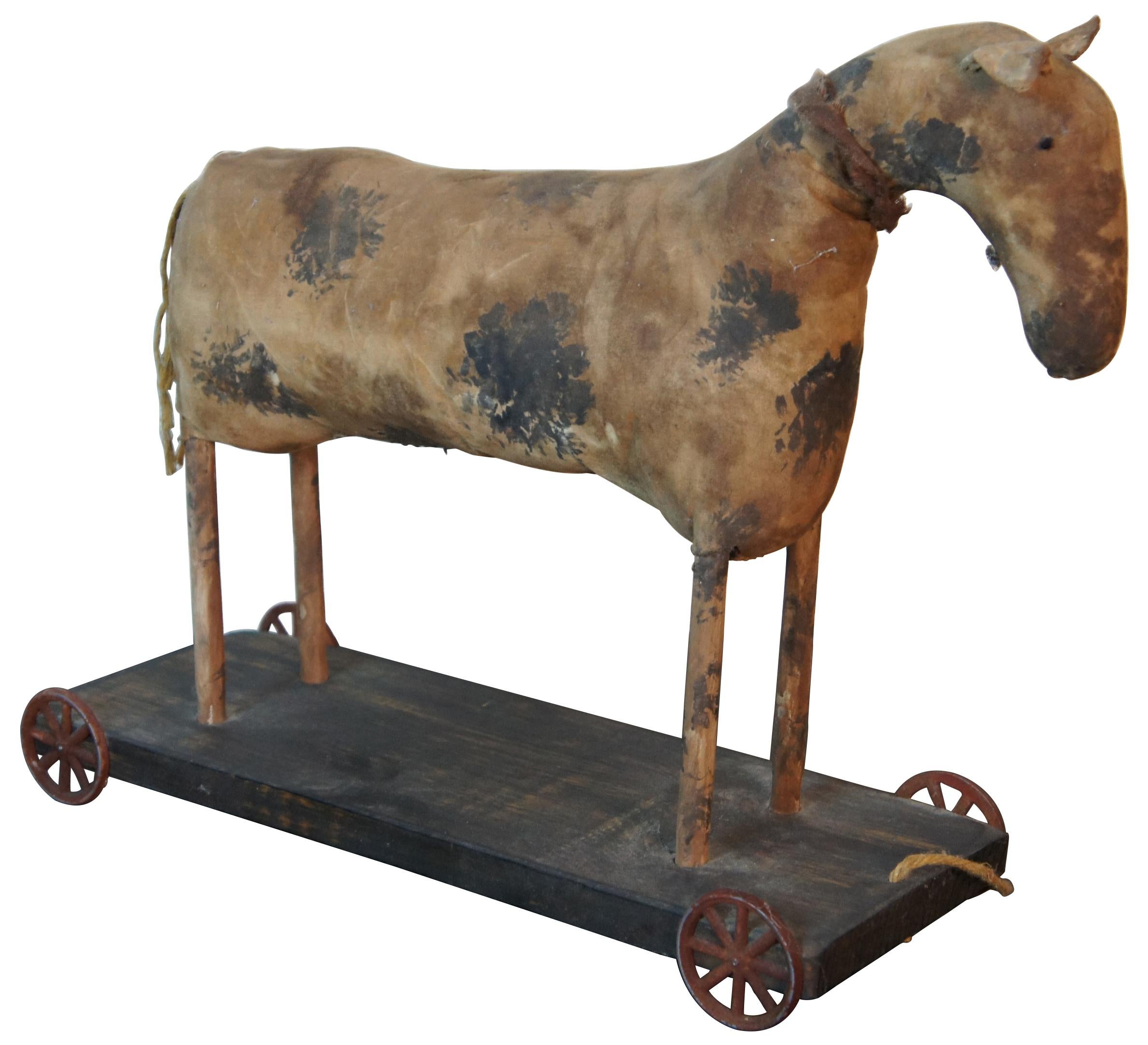 Antique Americana black and white spotted stuffed horse wheeled pull toy. Mounted to a pine base. Measures: 16