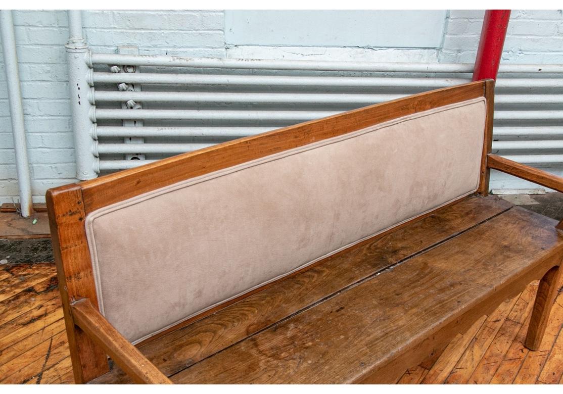Antique bench with side drawer. The bench with time softened wood with an inset custom faux-suede padded back cushion. The back has a slight angle and there is a traditional decorative front seat panel. One side of the bench has a storage drawer