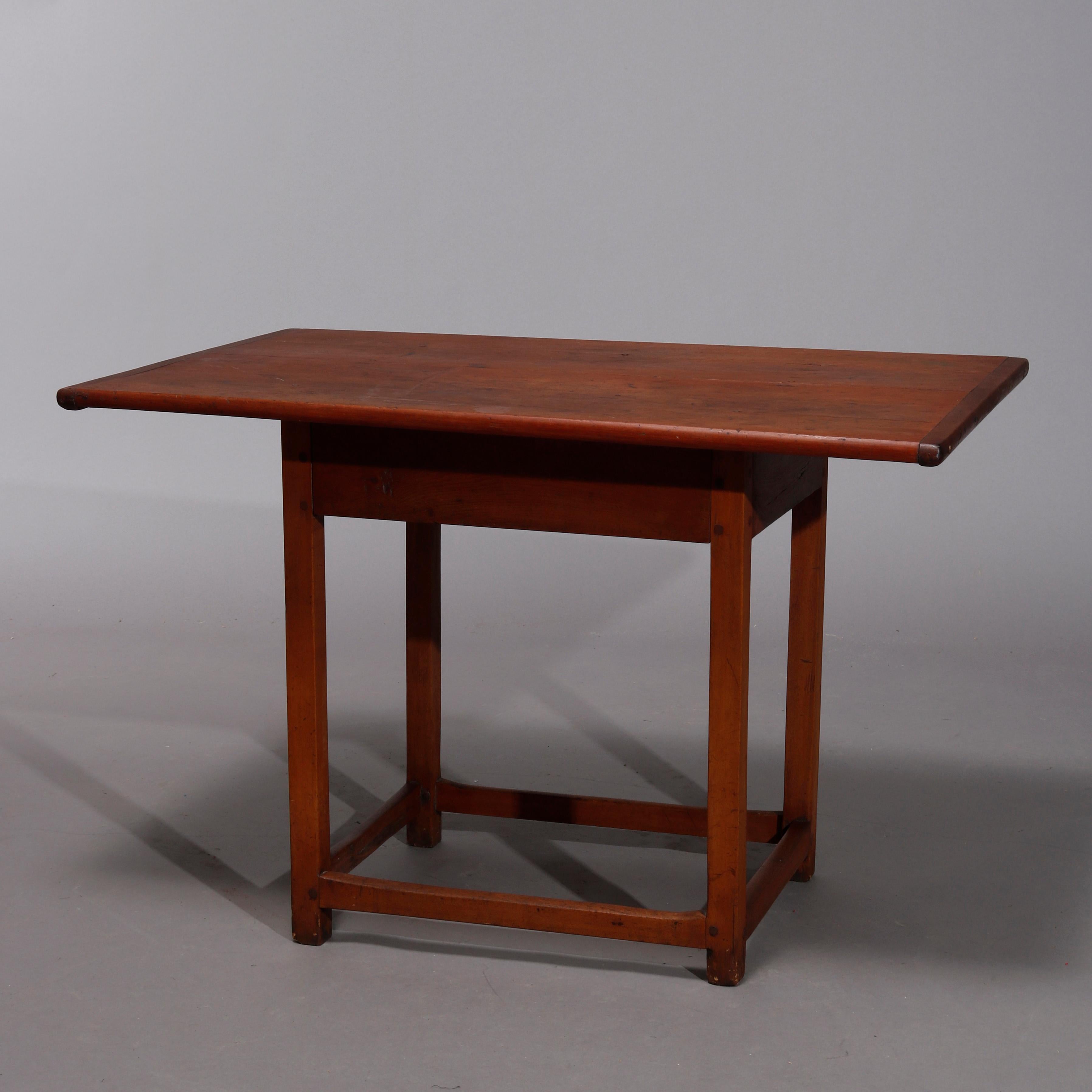 An antique Primitive Colonial breakfast or tavern table offers cherry construction with oversized top surmounting base with deep skirt and straight legs terminating in stretcher base, 18th century

Measures- 27