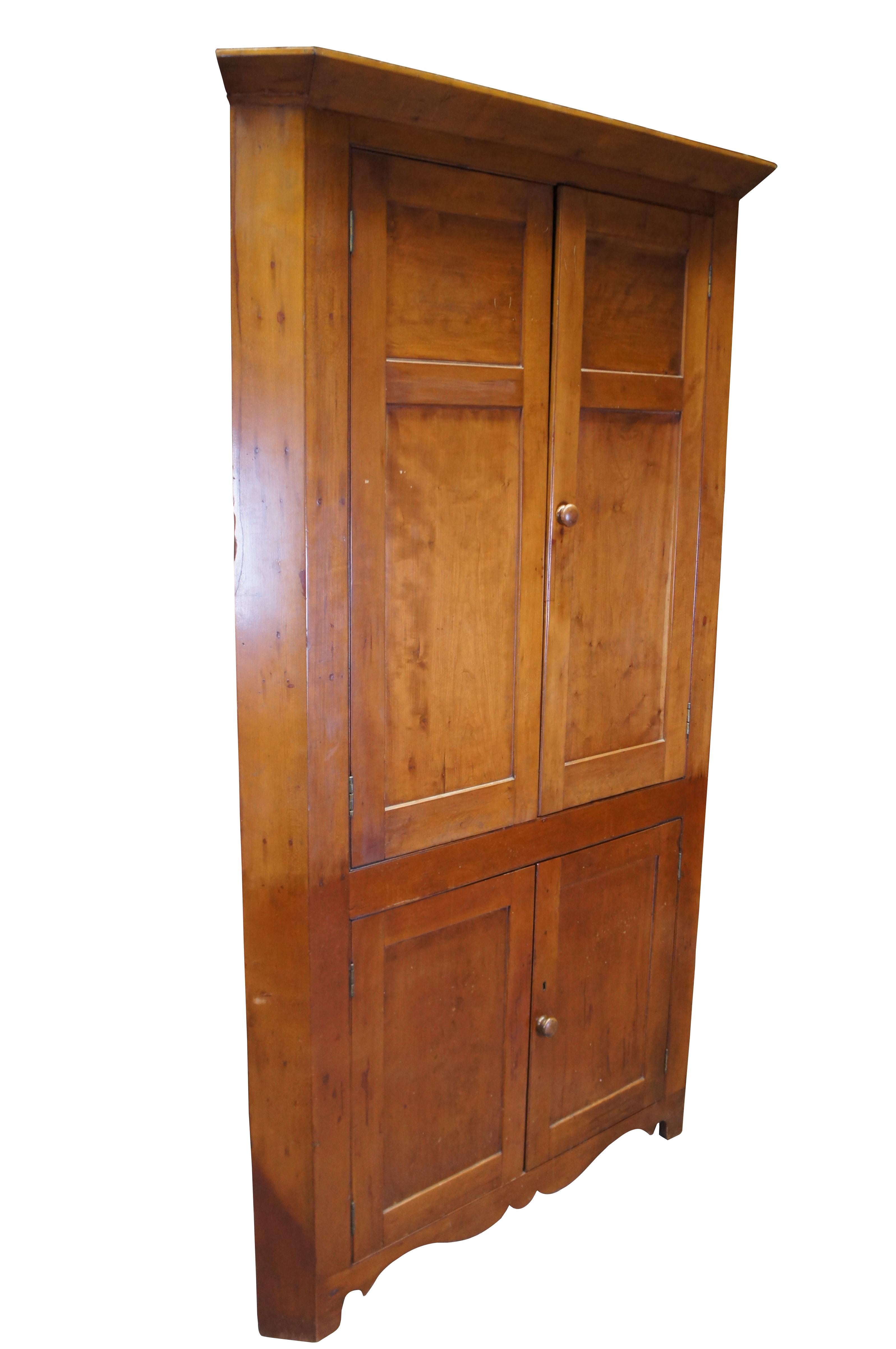 Antique American china cabinet / corner cupboard.  Made from cherry wood featuring triangular form with paneled doors that open to multiple storage shelves, some with plate grooves.

Dimensions:
81