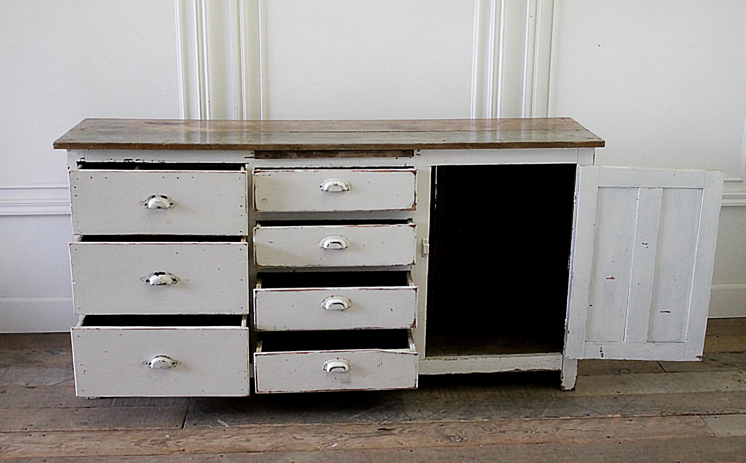 Antique European farmhouse style buffet server with wood top.
Late 19th century painted white primitive server with 7 drawers and single door with original hardware.
Original natural patina. There is a pullout / pull-out cutting or serving board