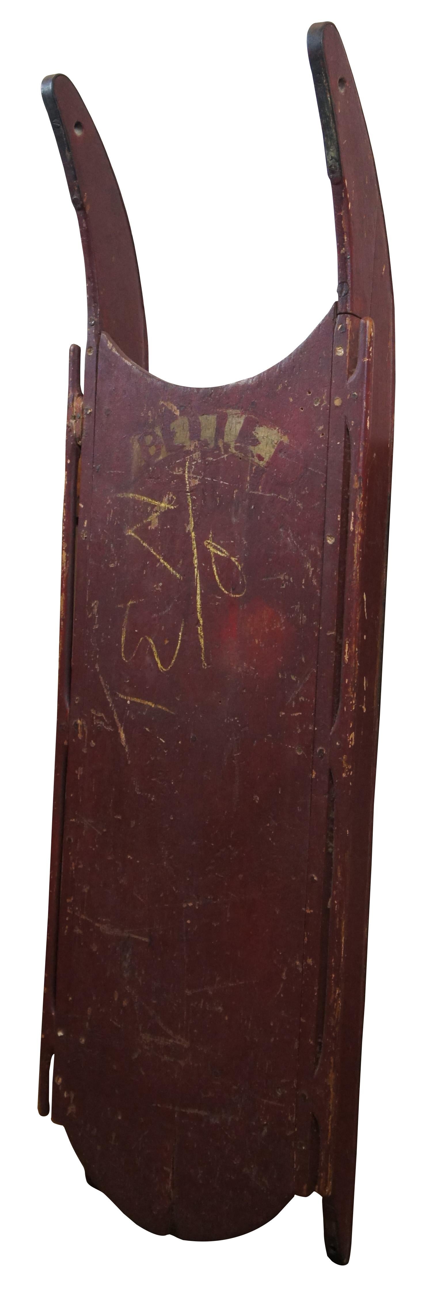 Antique Victorian wooden children’s sled with iron wrapped runners, painted dark red with the word “Belle” picked out in gold.