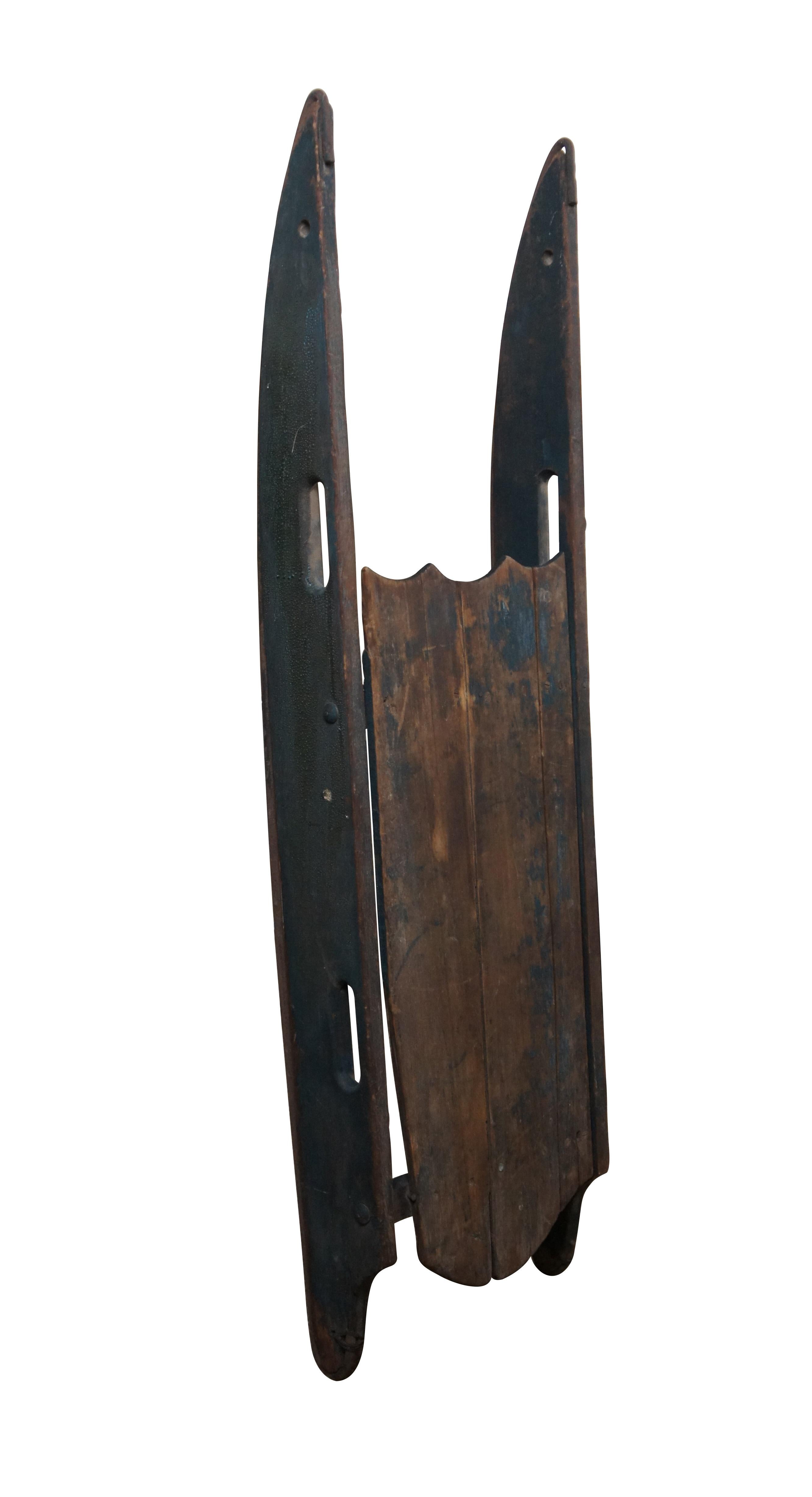 Antique late 19th to early 20th century wooden children's Christmas winter sled with worn dark green paint, cut out handles, and iron runners.

Dimensions:
42