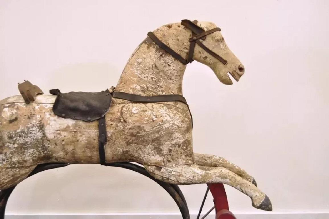 Antique Primitive Glider Rocking Hobby Horse Rustic Carved Wood Cast Iron Red. L'article comprend un cheval en bois sculpté, une base en bois peinte en rouge, des ferrures en fonte avec des étoiles, des sangles et une selle en cuir. L'attention