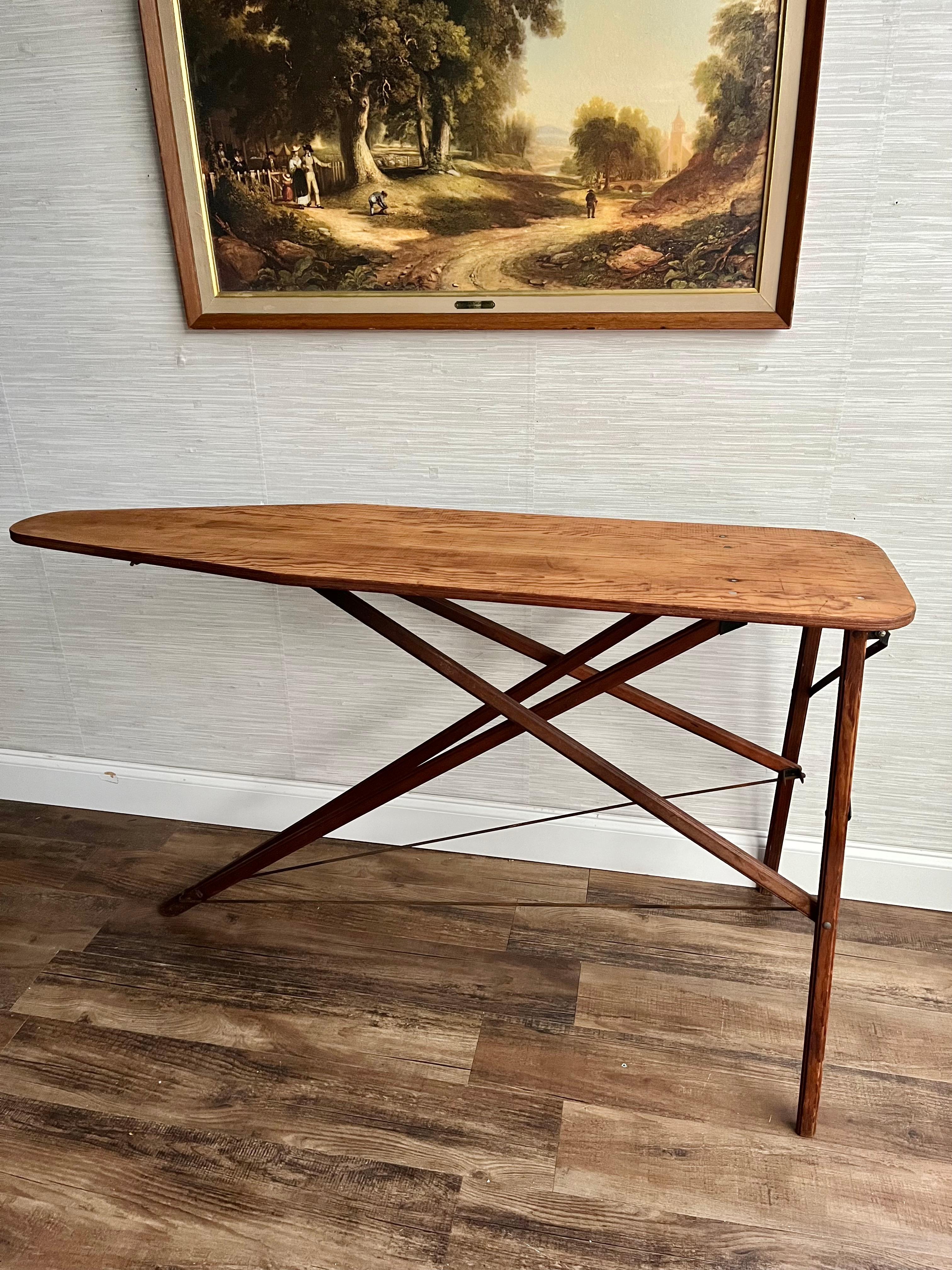 Rediscover the timeless appeal of our Antique Wooden Ironing Board, a beautifully preserved piece from the early 1900s that exudes rustic charm and functionality. This ironing board is crafted from richly grained wood, showcasing a stunning patina