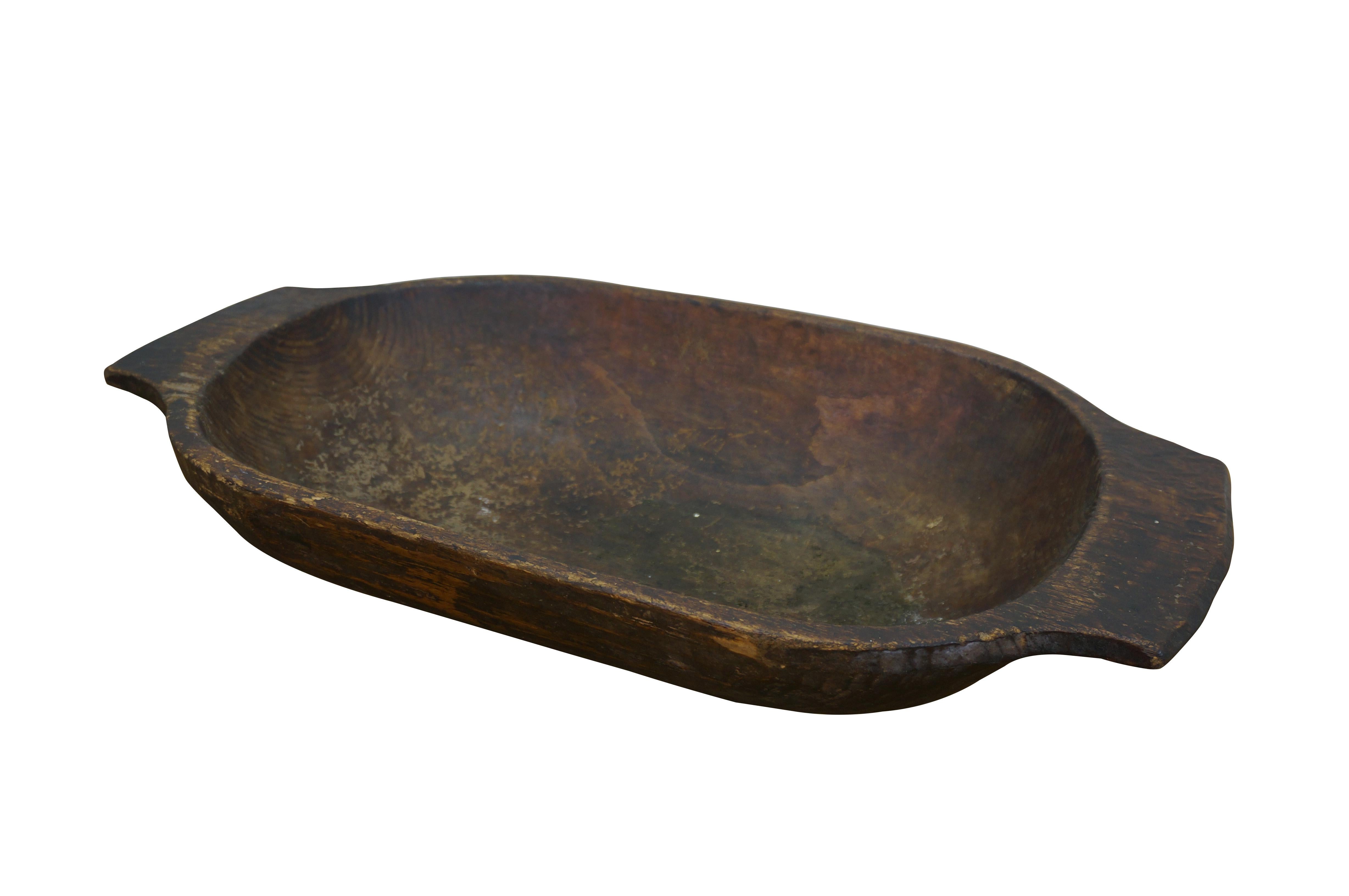 Antique hand hewn wooden dough bowl - rounded rectangular form with two flat handles at the ends and dark patina from use.

Dimensions:
24.5