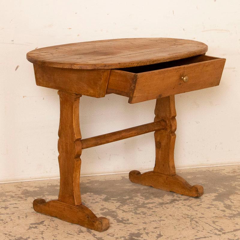 There is something endearing about this primitive oval side table. Is it the warmth of the aged pine, now distressed with minor cracks and gouges? You can clearly see the 3 planks that make up the top and simple but functional drawer(pull added