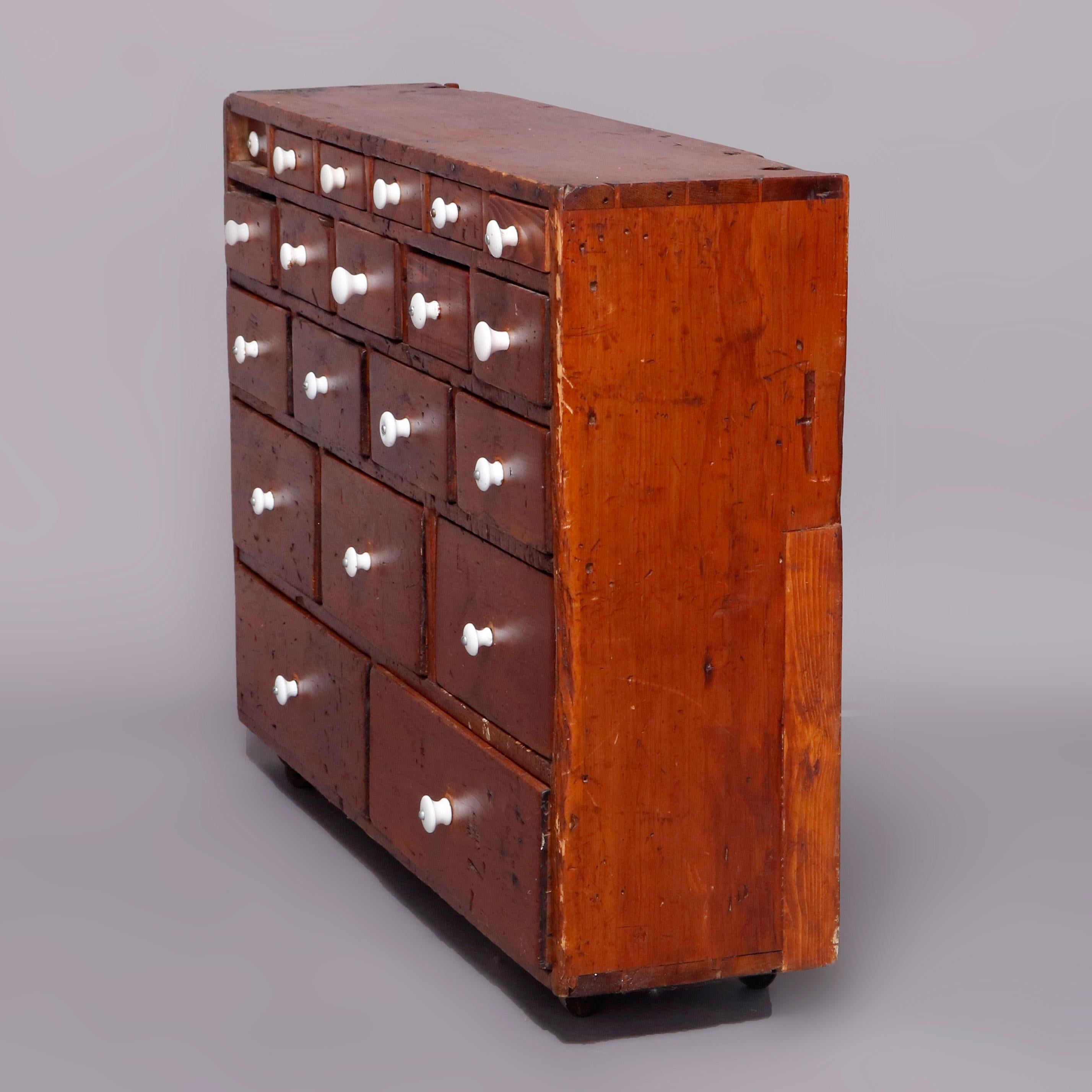 An antique primitive apothecary cabinet offers softwood construction having twenty graduated drawers with porcelain pulls and seaed on casters, 19th century

Measures: 28