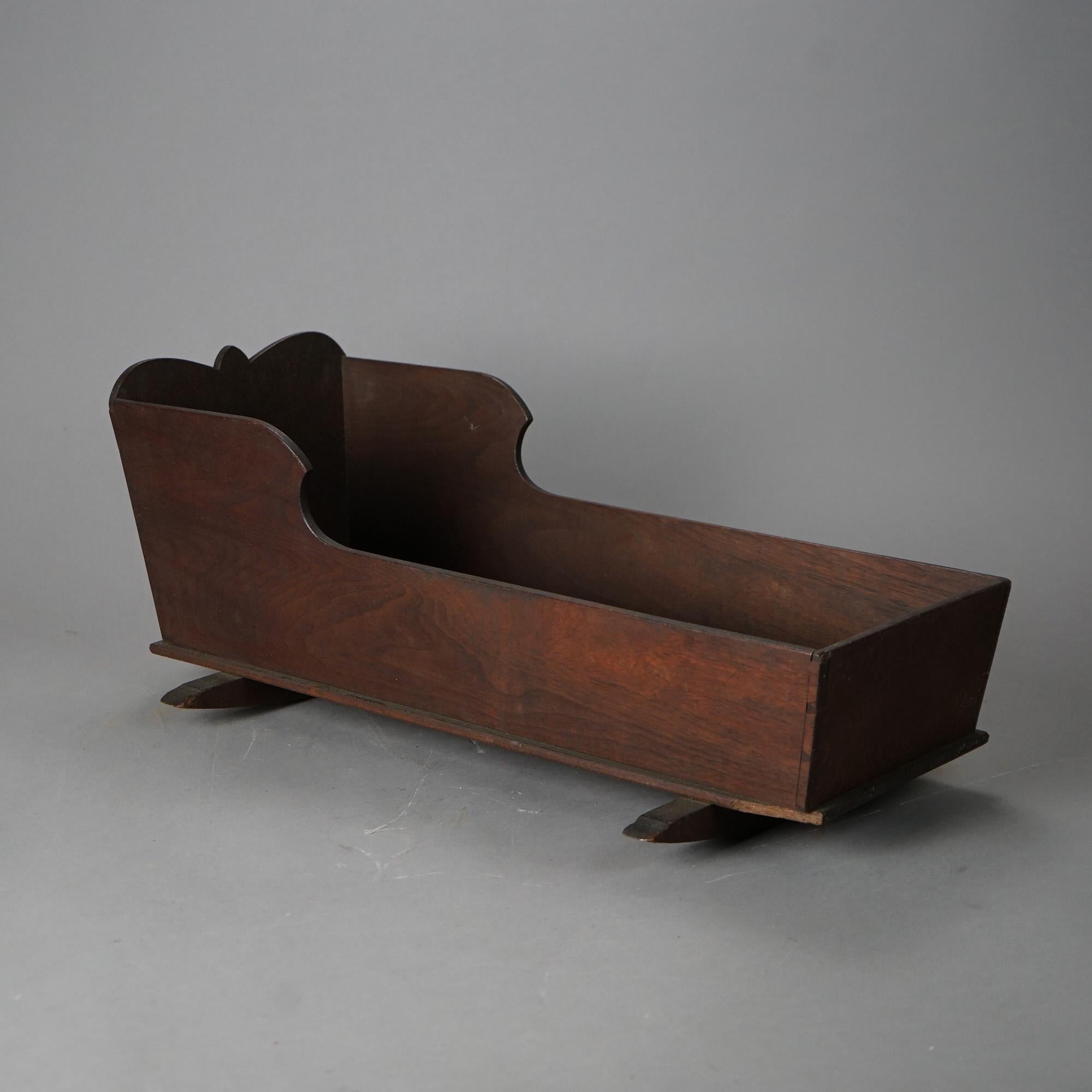 An antique primitive doll cradle offers walnut construction with shaped backboard, c1850

Measures - 9.25