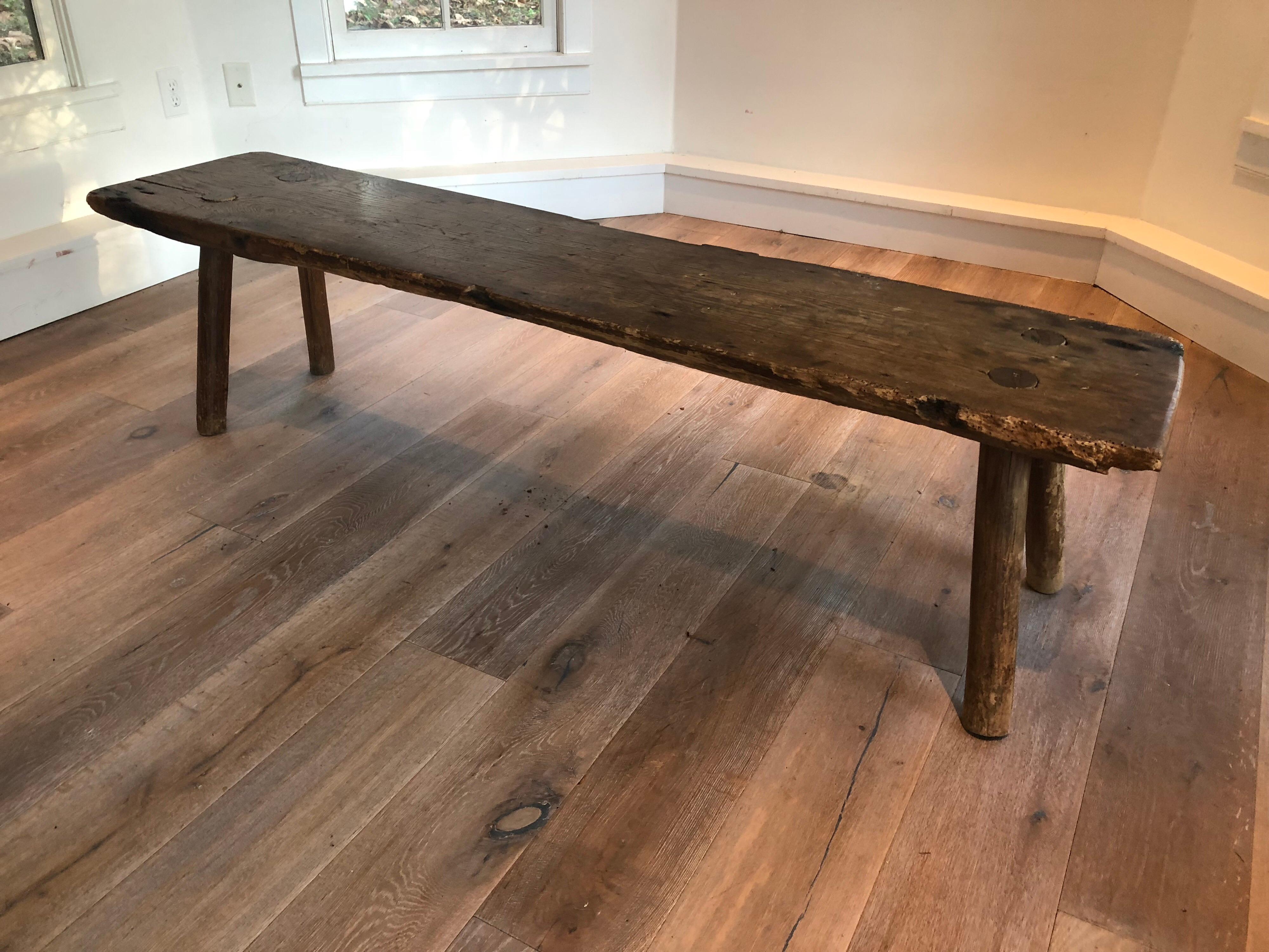 An antique primitive wood long bench. Great dowel construction and patina to wood. Chipping and wear along edges consistent with age and use.